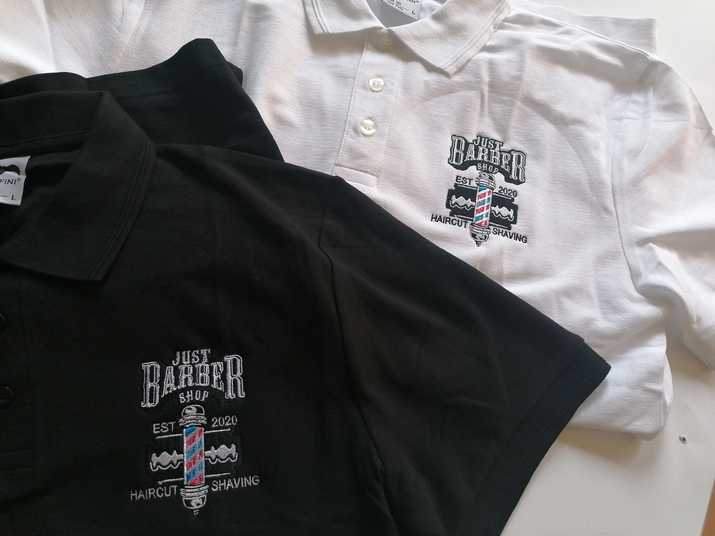 Haftowane logo zakładu barberskiego na czarnej i białej koszulce polo