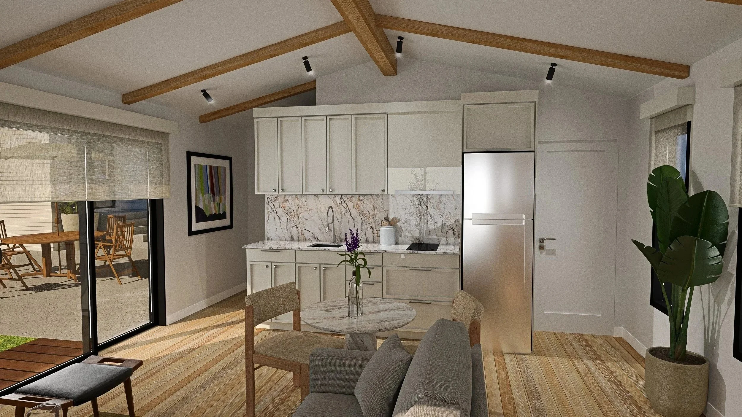 Modern kitchen with white cabinets, marble backsplash, stainless steel refrigerator, small round marble dining table with chairs, beige sofa, potted plant, artwork on wall, and sliding glass door leading to outdoor patio with wooden table and chairs.