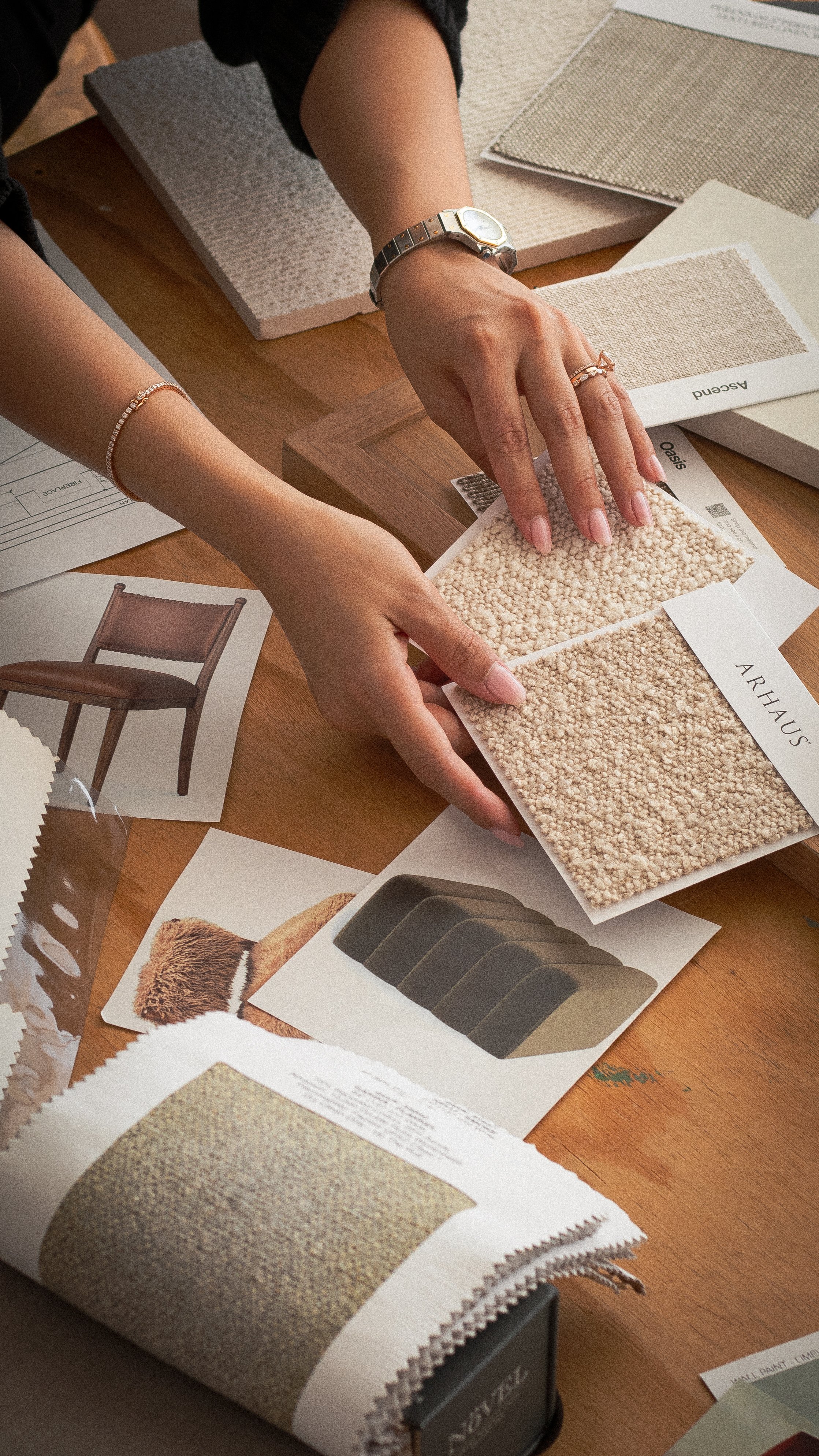 Person examining fabric samples and color swatches for furniture design at a desk.