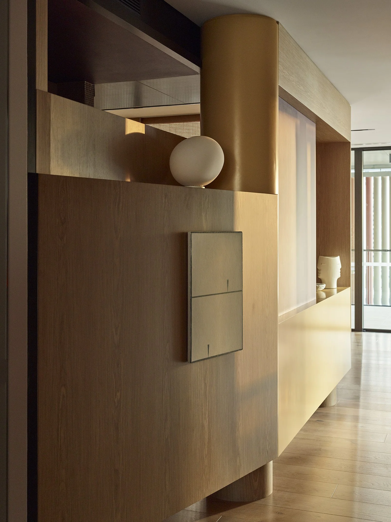 Modern interior with wooden and metallic decor, a white spherical lamp, and a beige sculpture of a head.