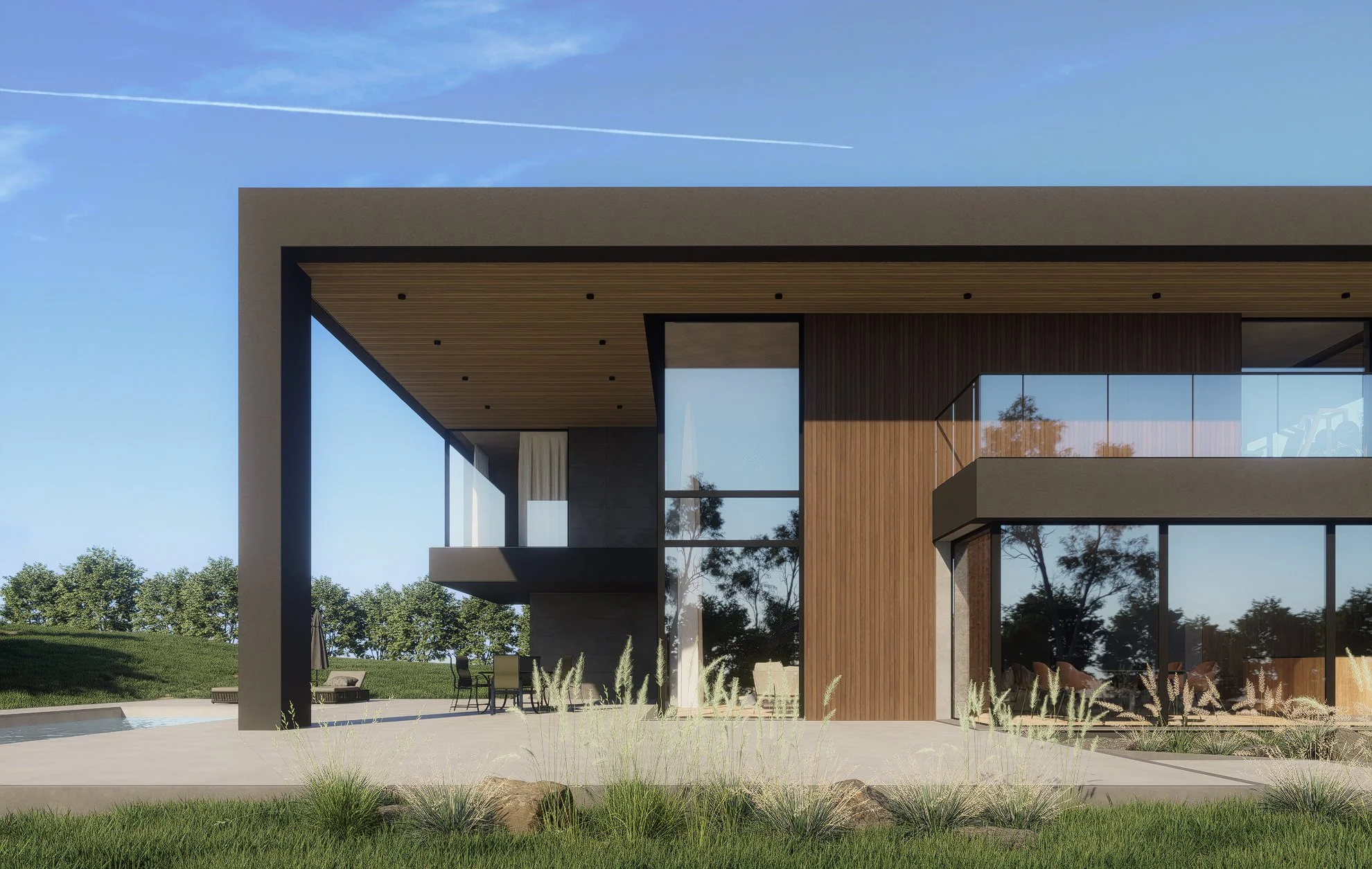 Modern house with large glass windows, wooden paneling, and a spacious outdoor patio with seating, surrounded by green grass and trees, under a clear blue sky.