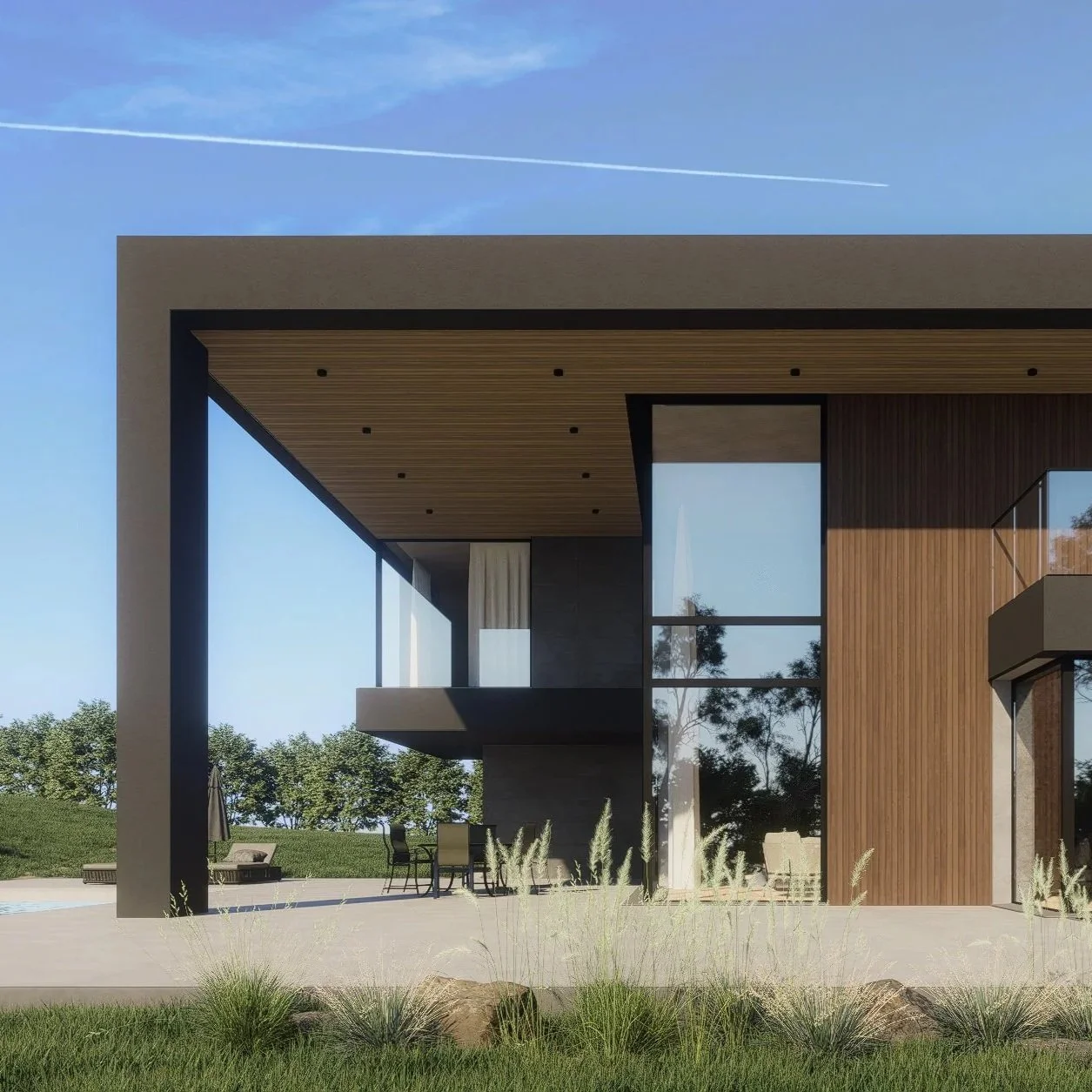 Modern house with large glass windows, wooden and concrete exterior, outdoor patio with table and chairs, greenery, and blue sky.