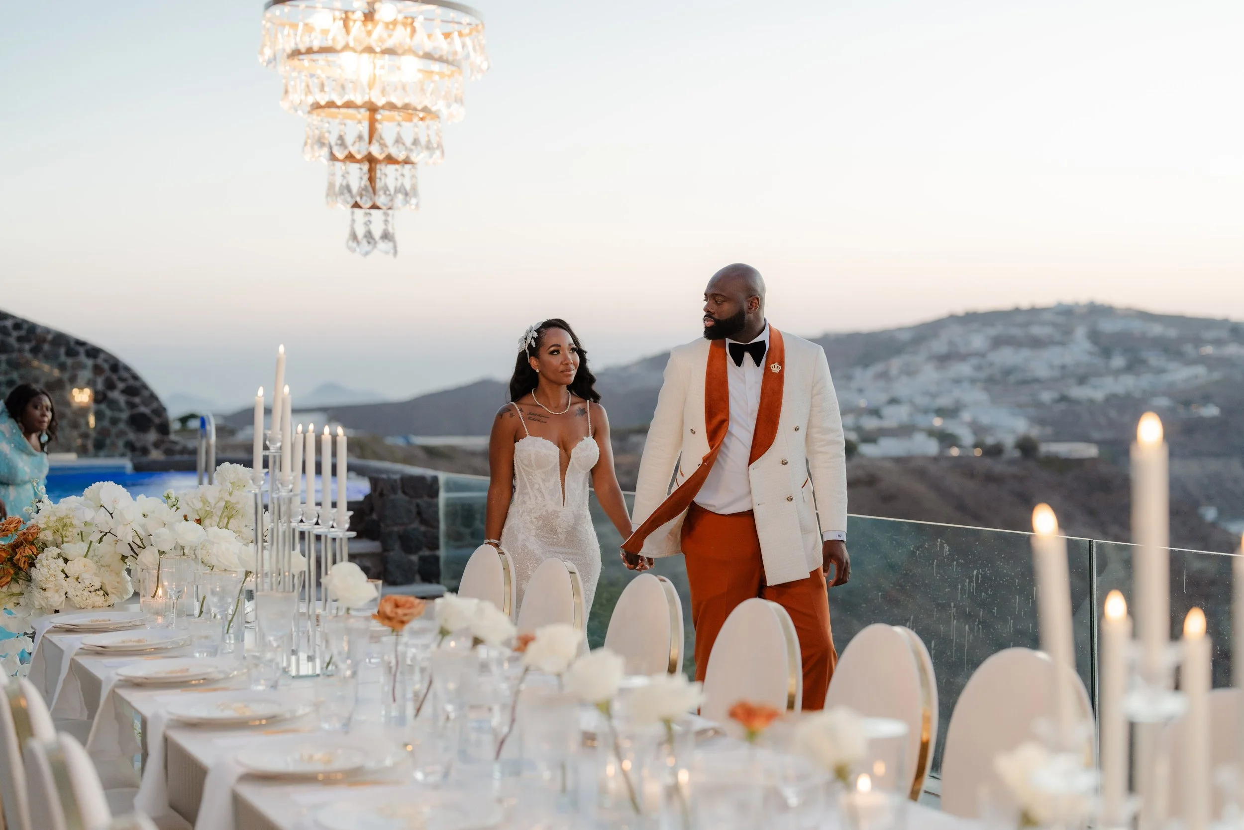 Luxury Wedding Reception in Santorini, Greece
The couple pose at their elegant reception setup surrounded by chandeliers and refined décor. A glamorous highlight of a luxury destination wedding in Greece.