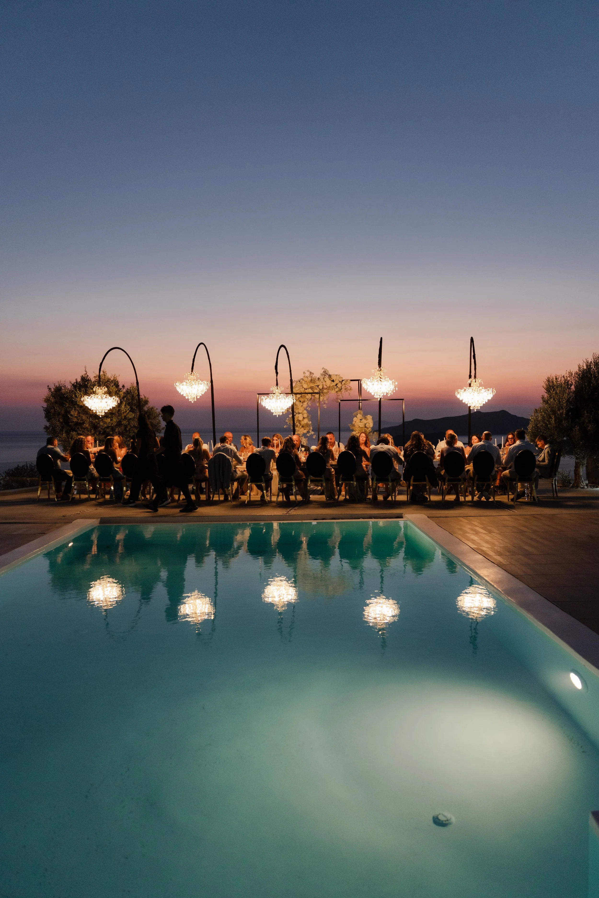 Luxury Wedding Night Celebration in Greece
As night falls, the poolside reception glows with chandeliers and candlelight. A sophisticated and glamorous setting for a luxury wedding in Santorini, Greece.