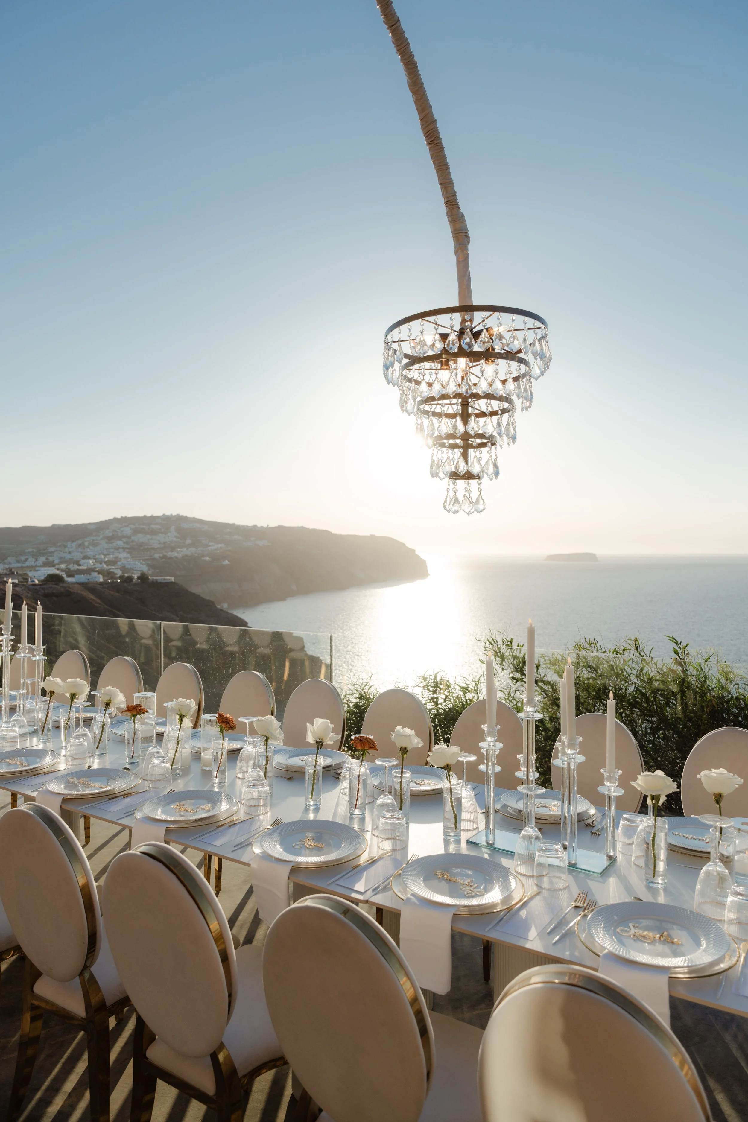 Luxury Wedding Reception in Greece
Round tables adorned with white florals and chandeliers create a glamorous reception atmosphere in Santorini. A breathtaking setting for a luxury destination wedding in Greece.