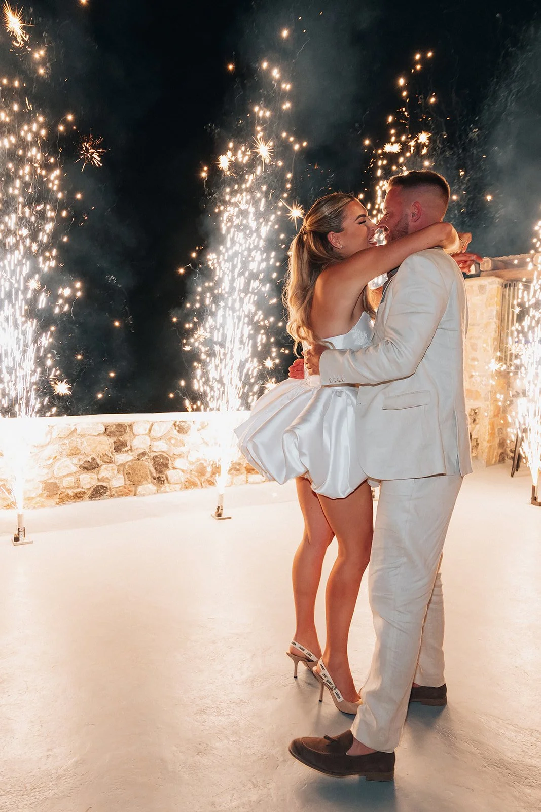 Newlyweds enjoying their magical first dance surrounded by fireworks and romance at a luxury Santorini wedding.