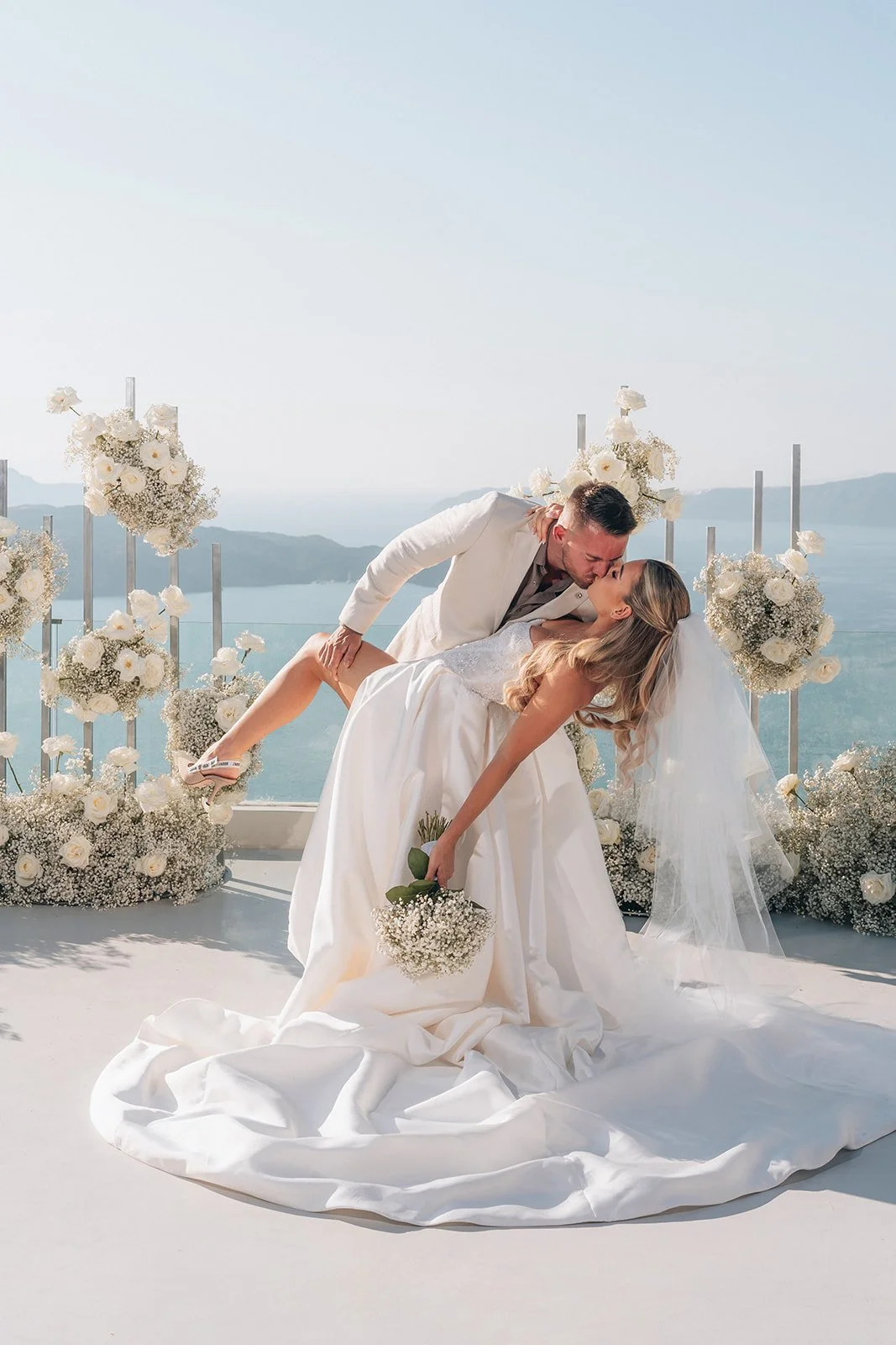 Groom lifting the bride in a joyful candid moment right after their Santorini wedding ceremony.