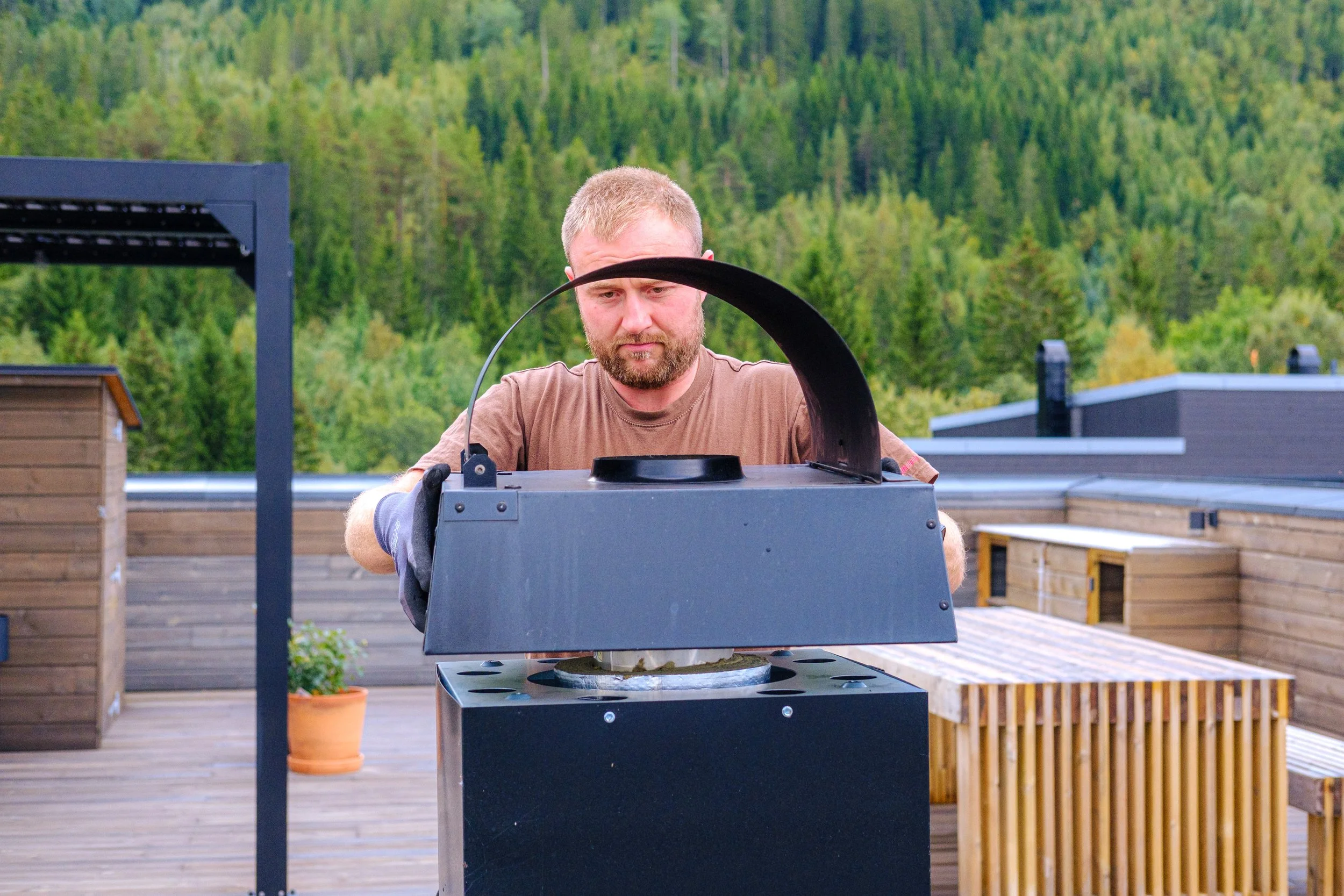 Andreas Naavik på en takterrasse, og fester ny pipehatt.