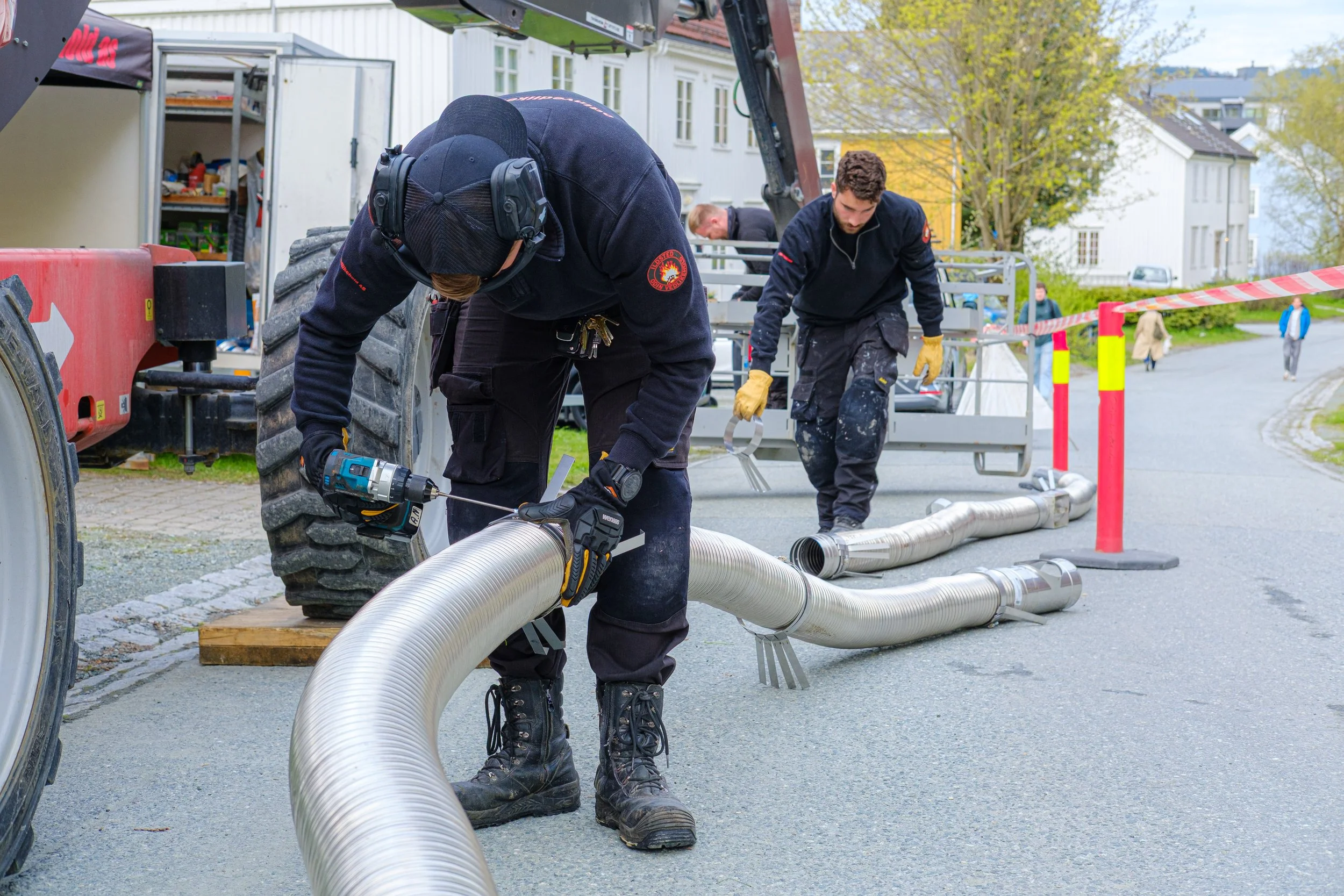 To personer som jobber med å koble sammen rør til vedlikehold av skorstein.