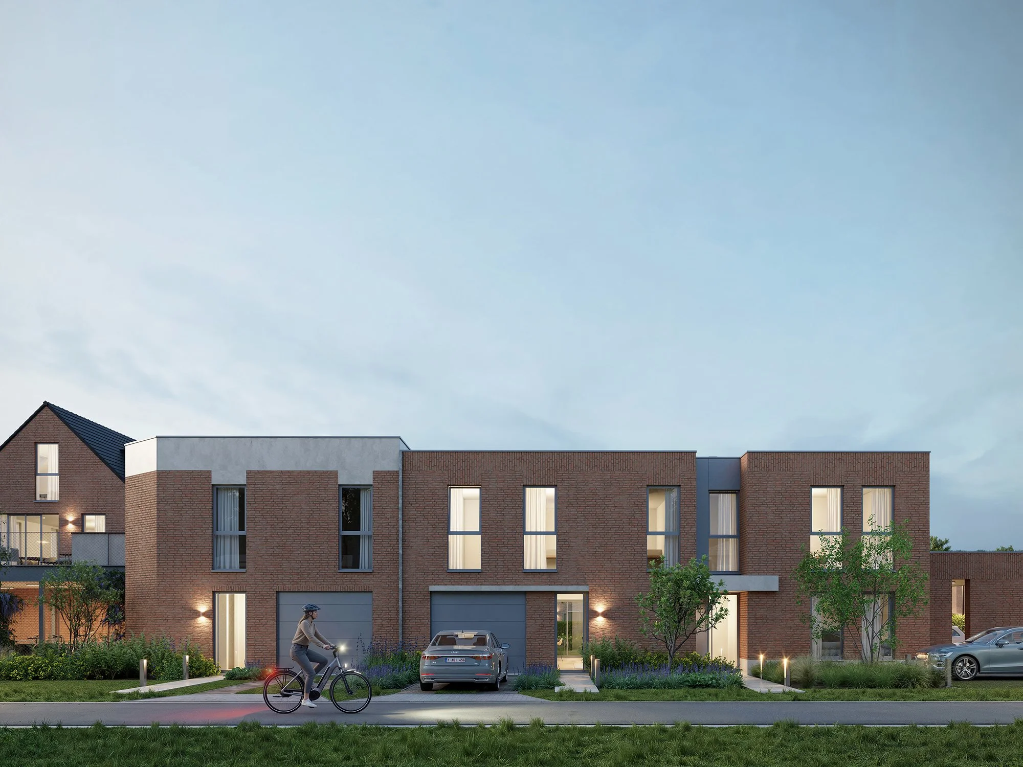 Moderne appartementengebouw met brick en wit gevel, verlichte ingangen en grote ramen. Voor- en achtertuinen met bomen en planten. Fietsende persoon op de weg, opgelichte auto's in de parkeergelegenheid, avondlicht met een blauwe lucht.