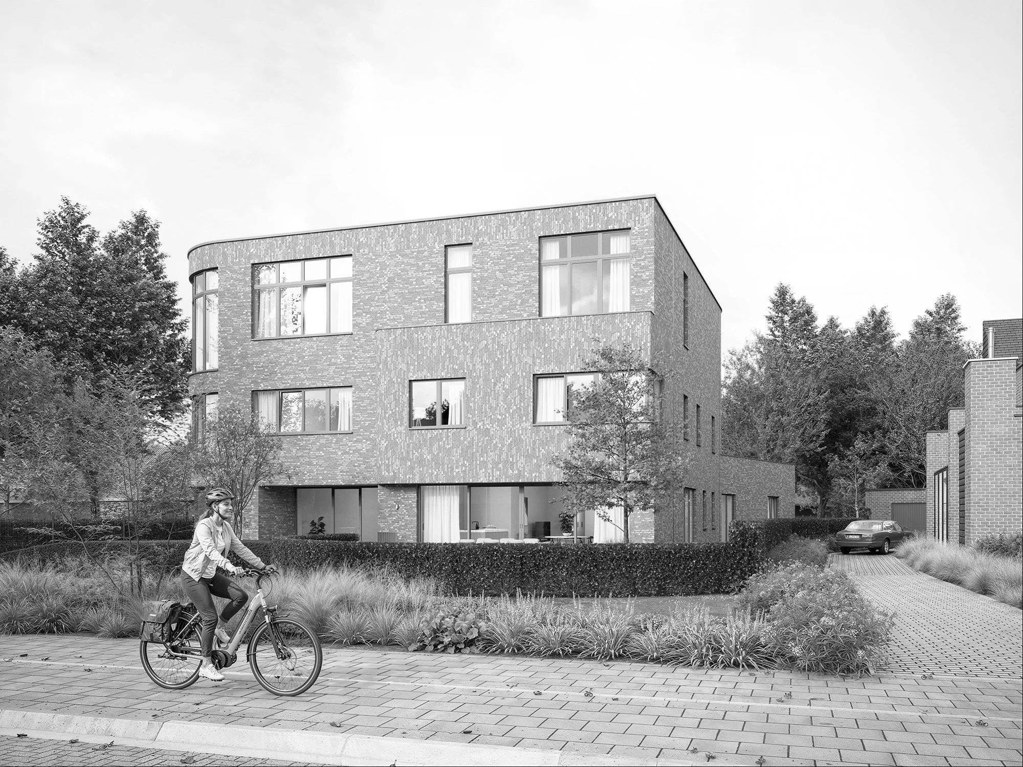 Vrouw fietst door een park met een modern appartementengebouw op de achtergrond.