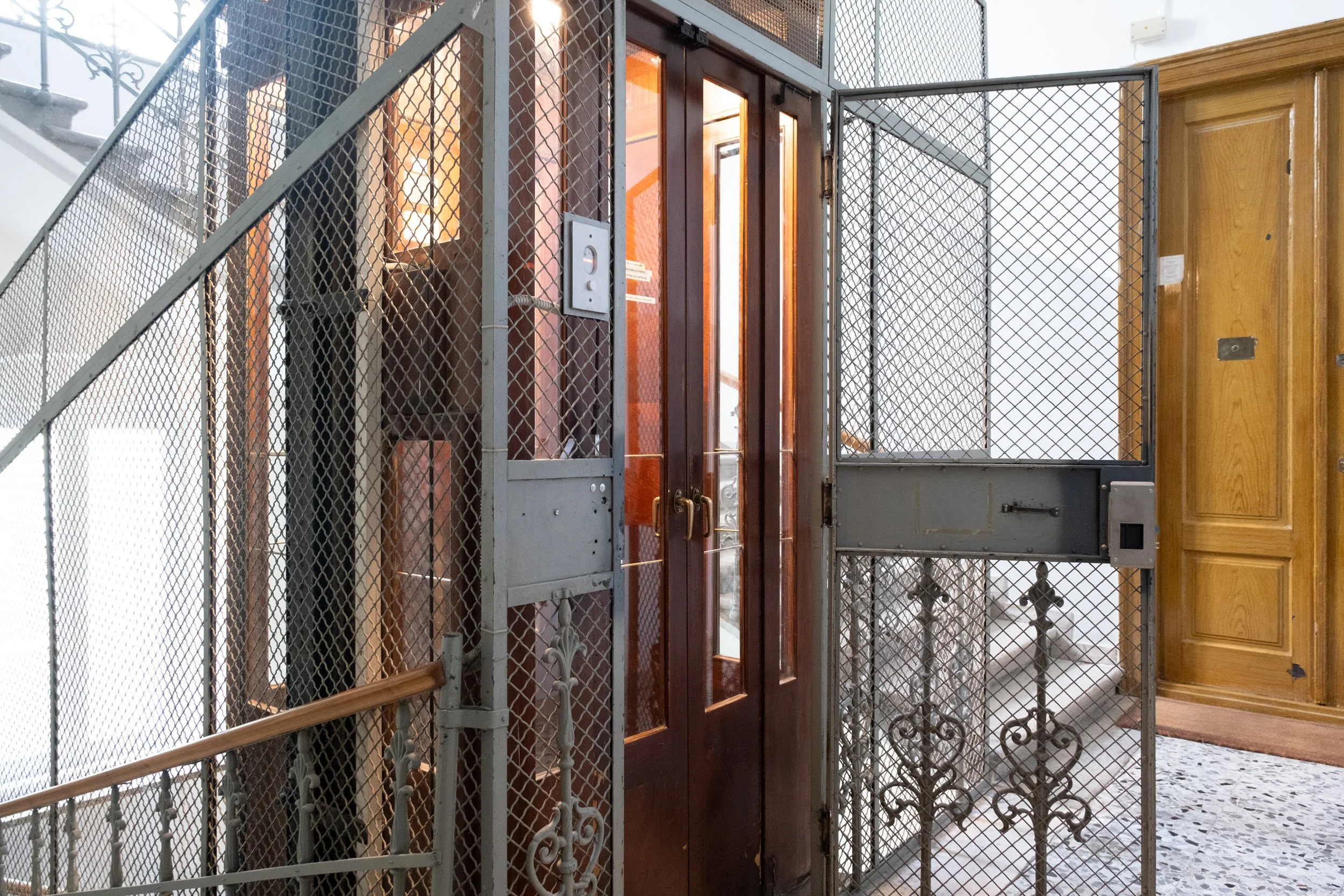 Ascensore in edificio con cancello di metallo e sbarre in ferro battuto.