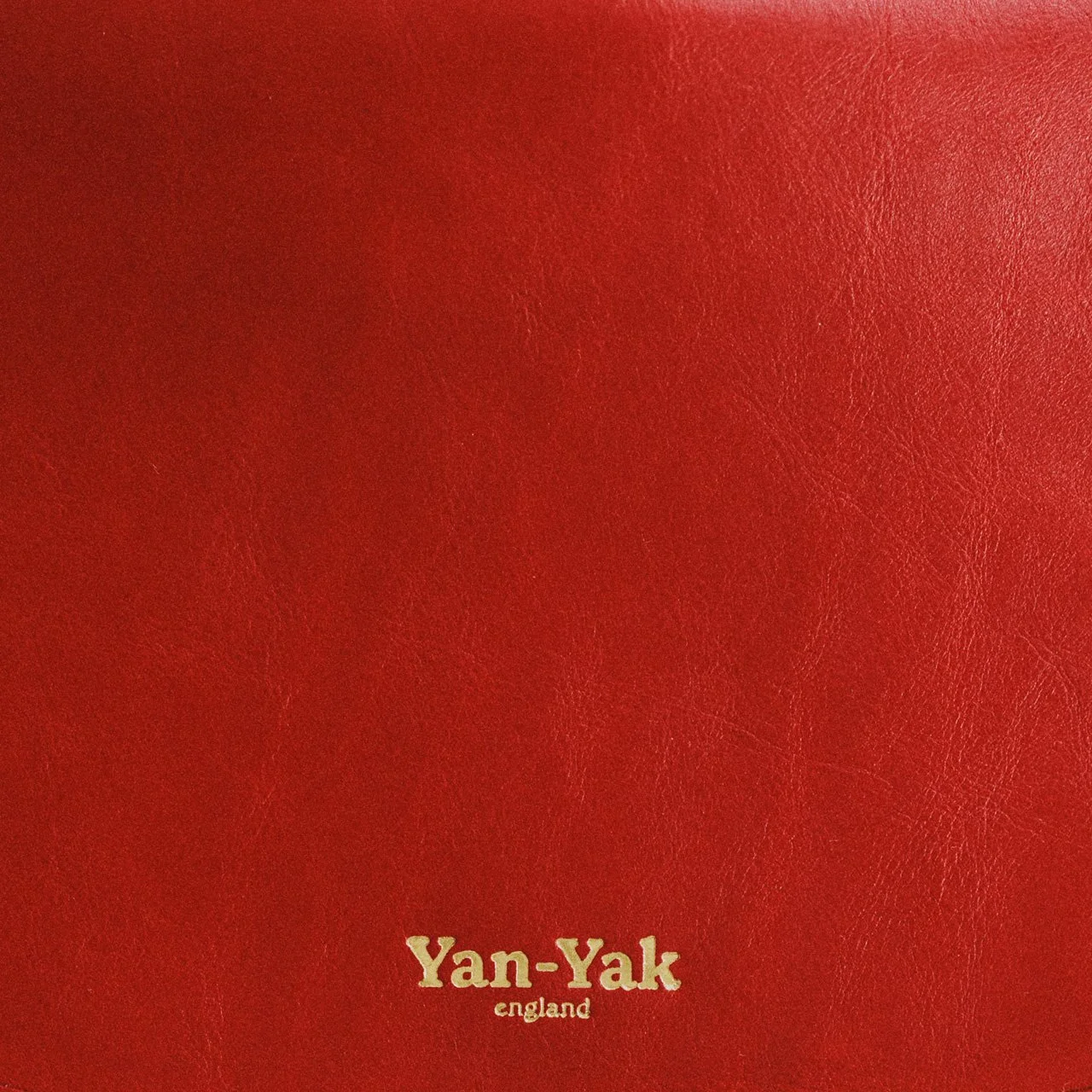 Close-up of red leather surface with gold text reading 'Yan-Yak, England' at the bottom
