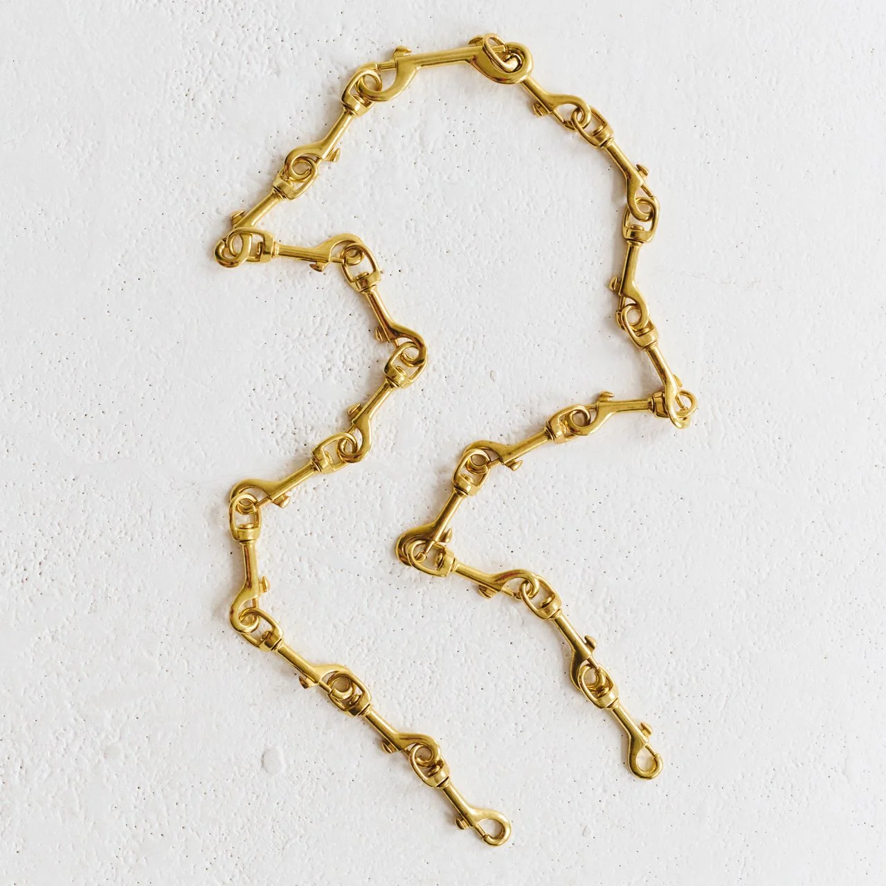 Gold chain strap on white textured background.