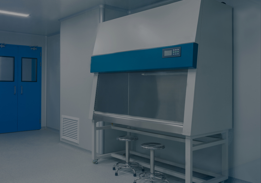 A laboratory clean bench with a digital control panel and two stools, located next to blue storage cabinets in a sterile environment.