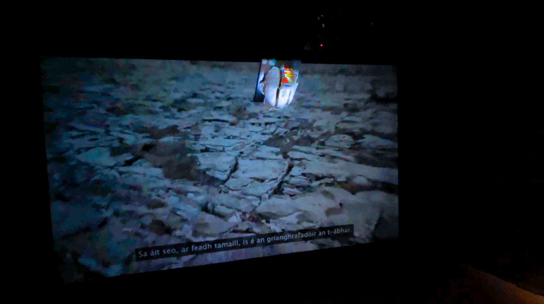 Tripartite, (2024). Installation #4.
Background wall AV projection, Cosán film, with foreground suspended sculptural form displaying series of projected images.