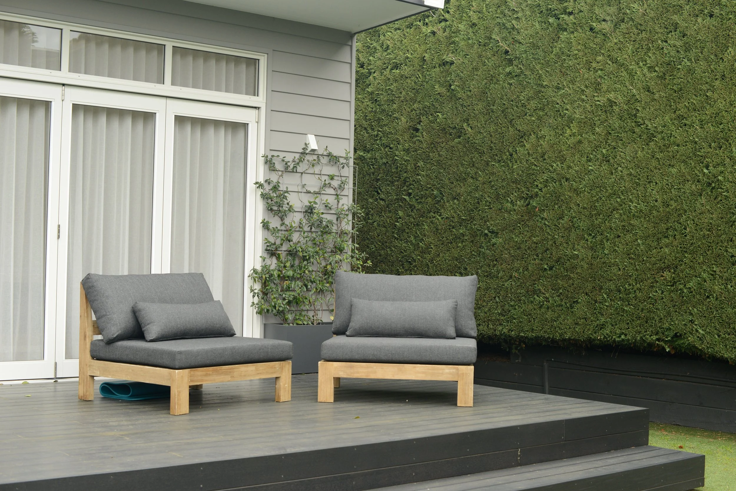 A cozy outdoor deck at Driftwood Studio Mt Eliza with two grey cushioned chairs on a wooden deck. Inviting space and room to relax during yoga retreats.