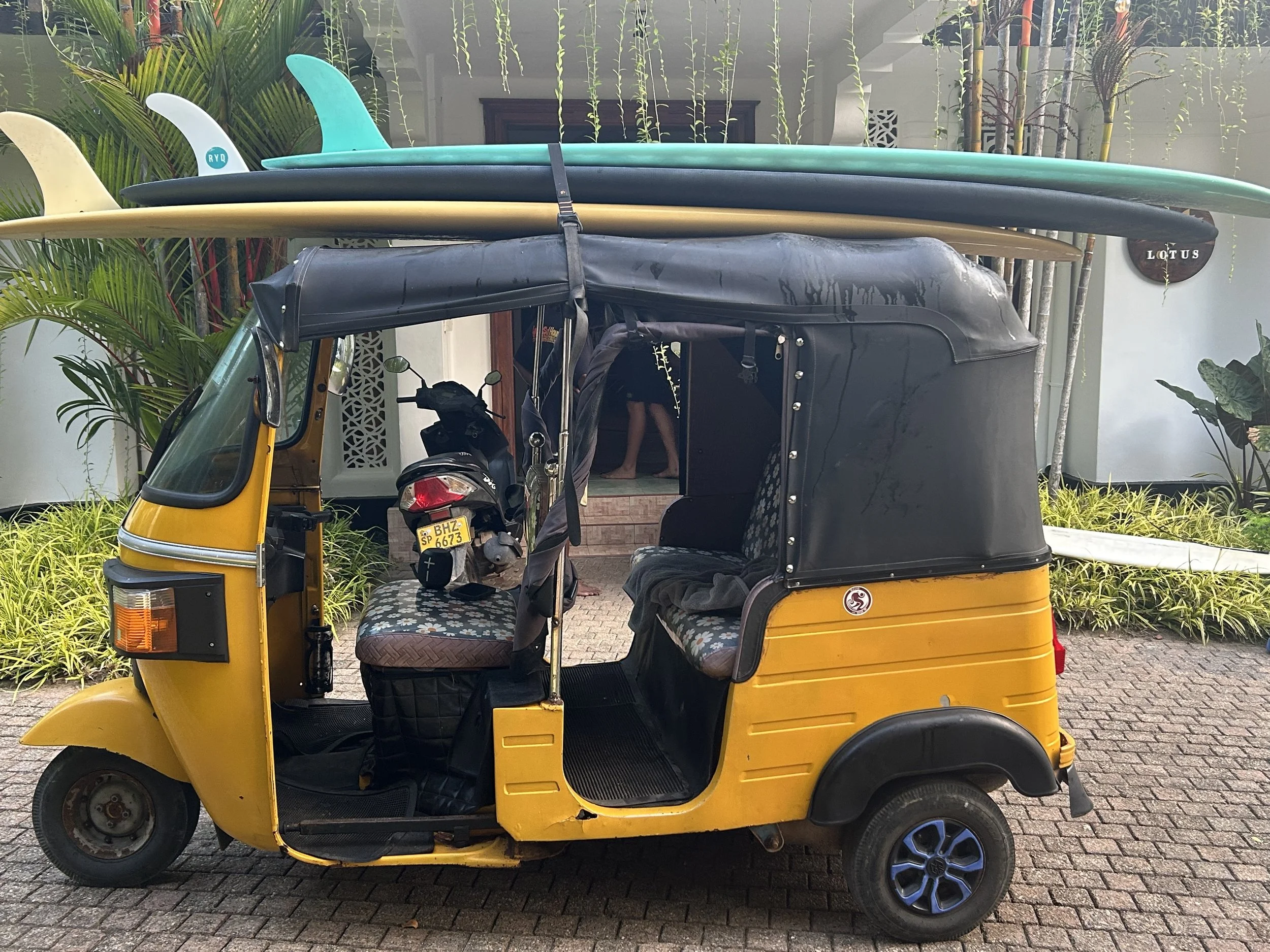 A tuk tuk with surfboards on the roof in sri lanka