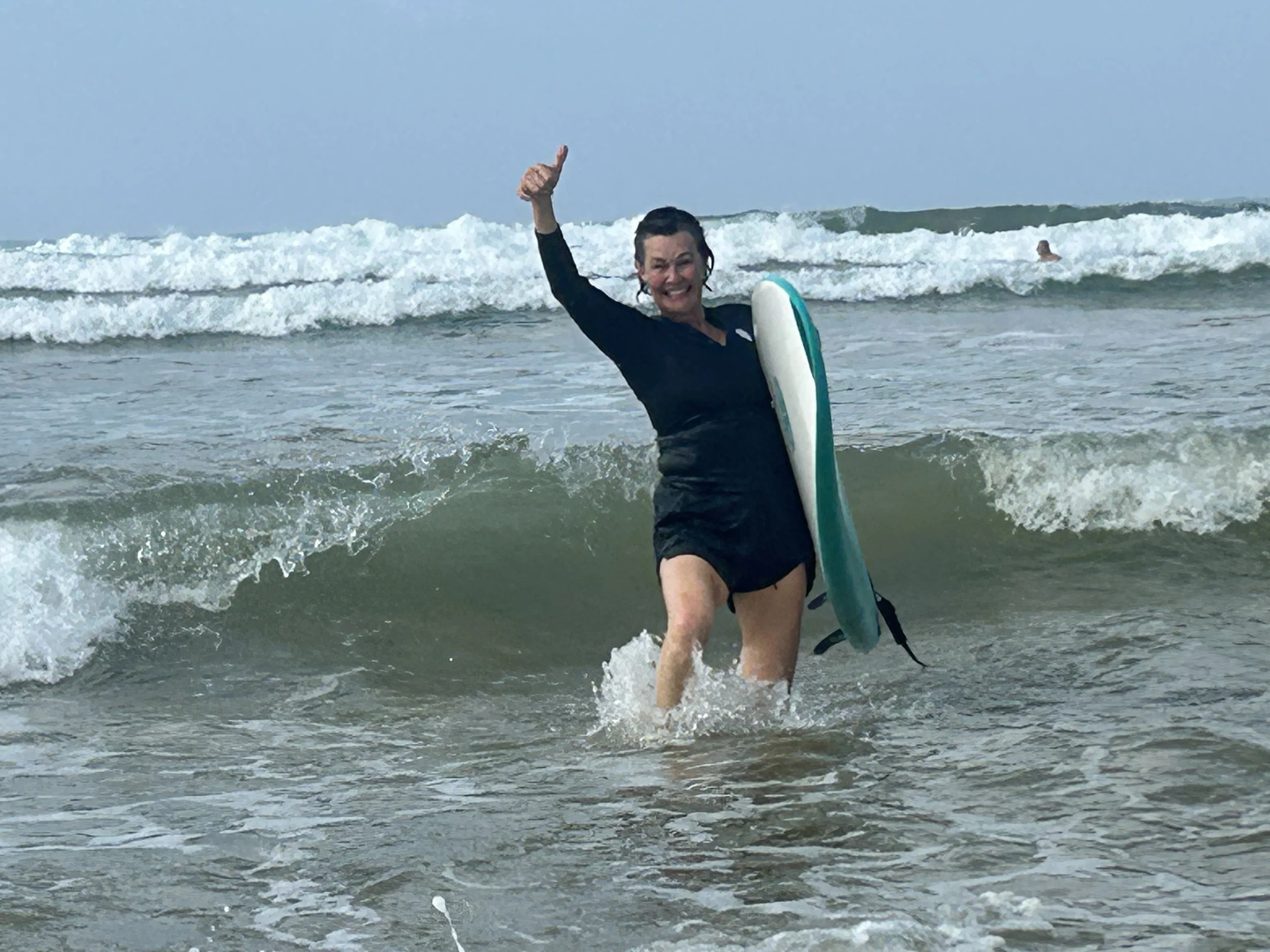 A happy beginner surfer coming out of the water in sri lanka after catching her fist wave