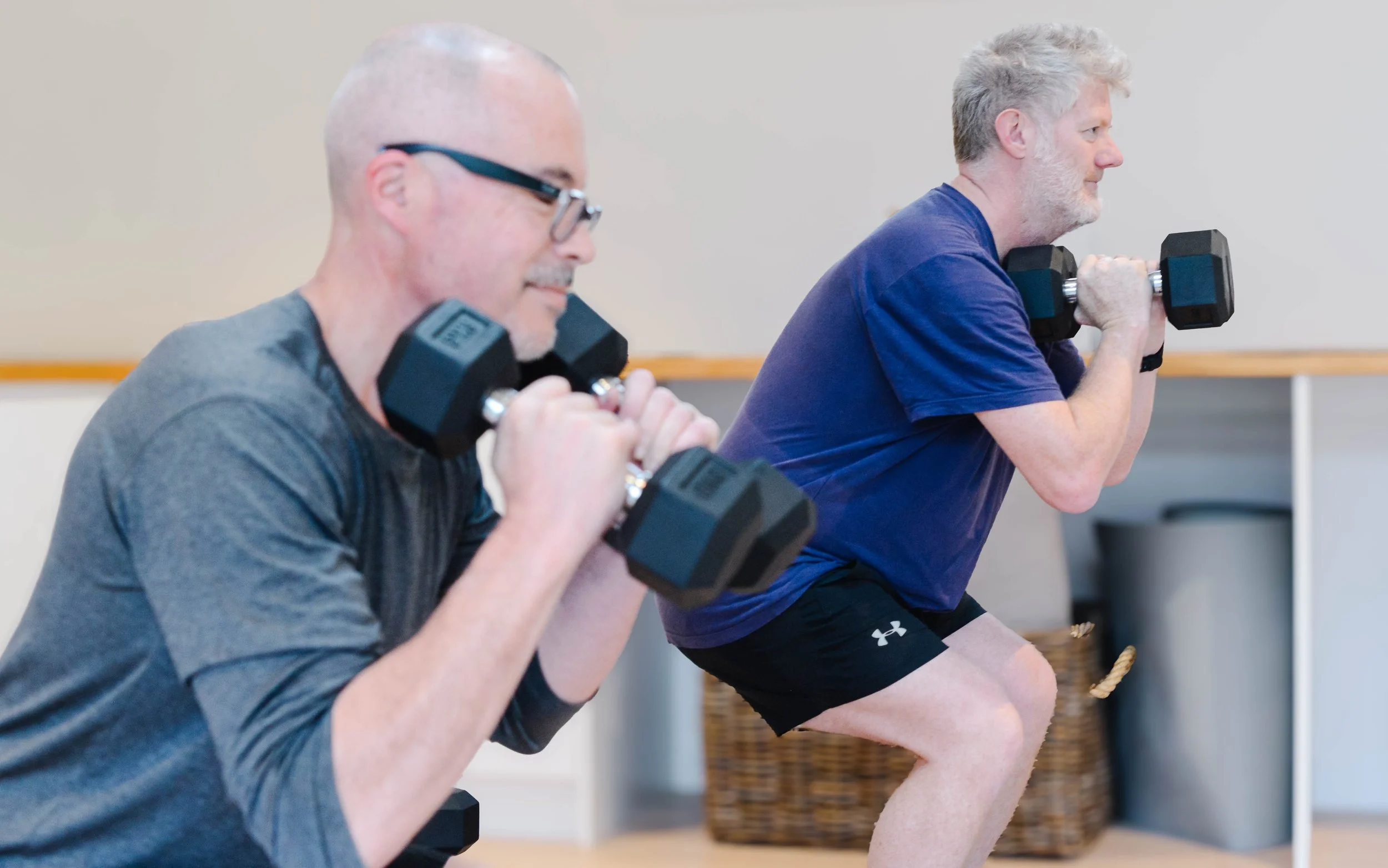 A group of women doing strength work in Driftwood studio, Mt Eliza on yoga mats, with an instructor assisting a student from behind
