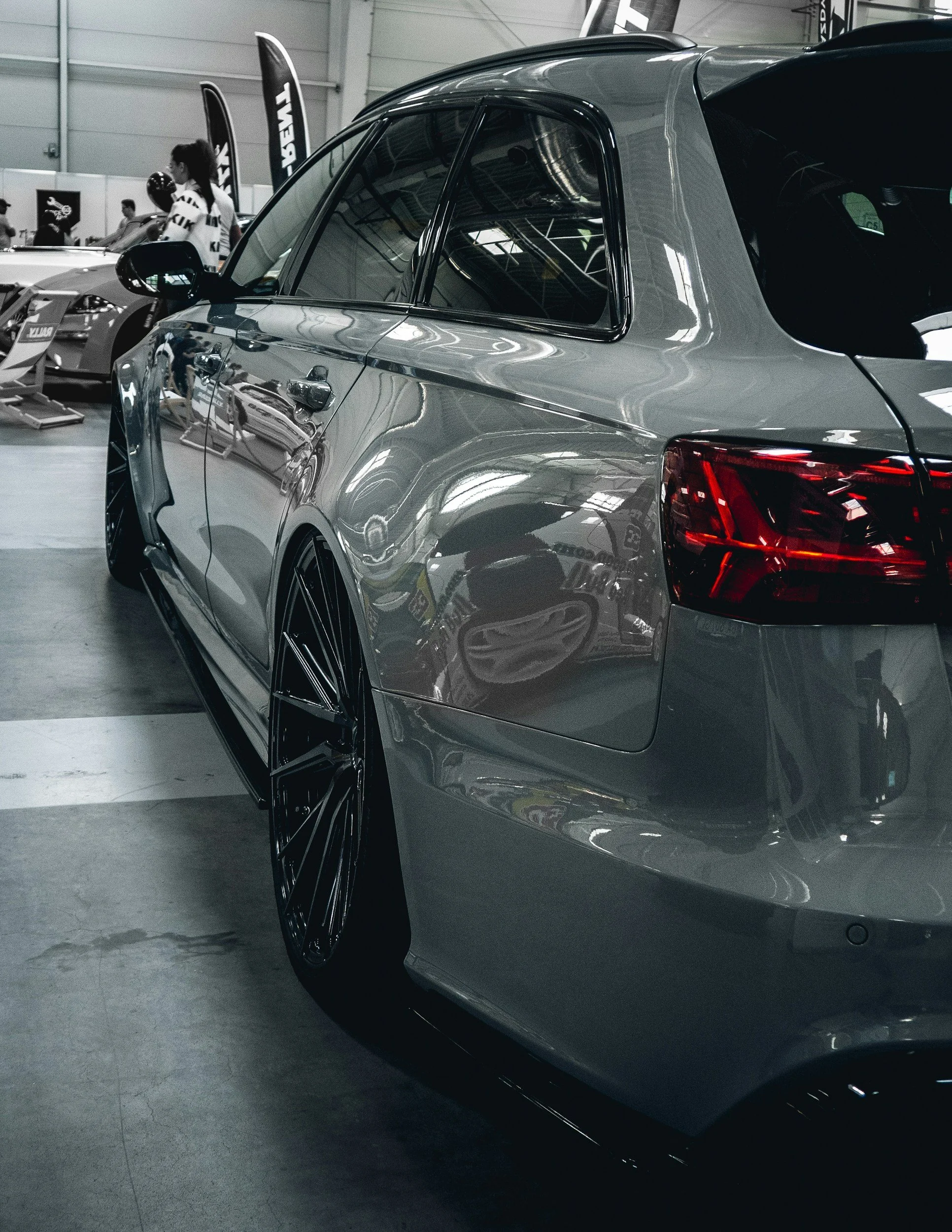 A silver luxury car displayed at an indoor auto show.