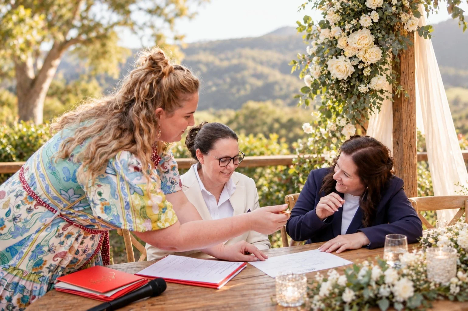 Maddie Hayes, Gold Coast Hinterland wedding celebrant, laughing with a couple as they sign their marriage certificate