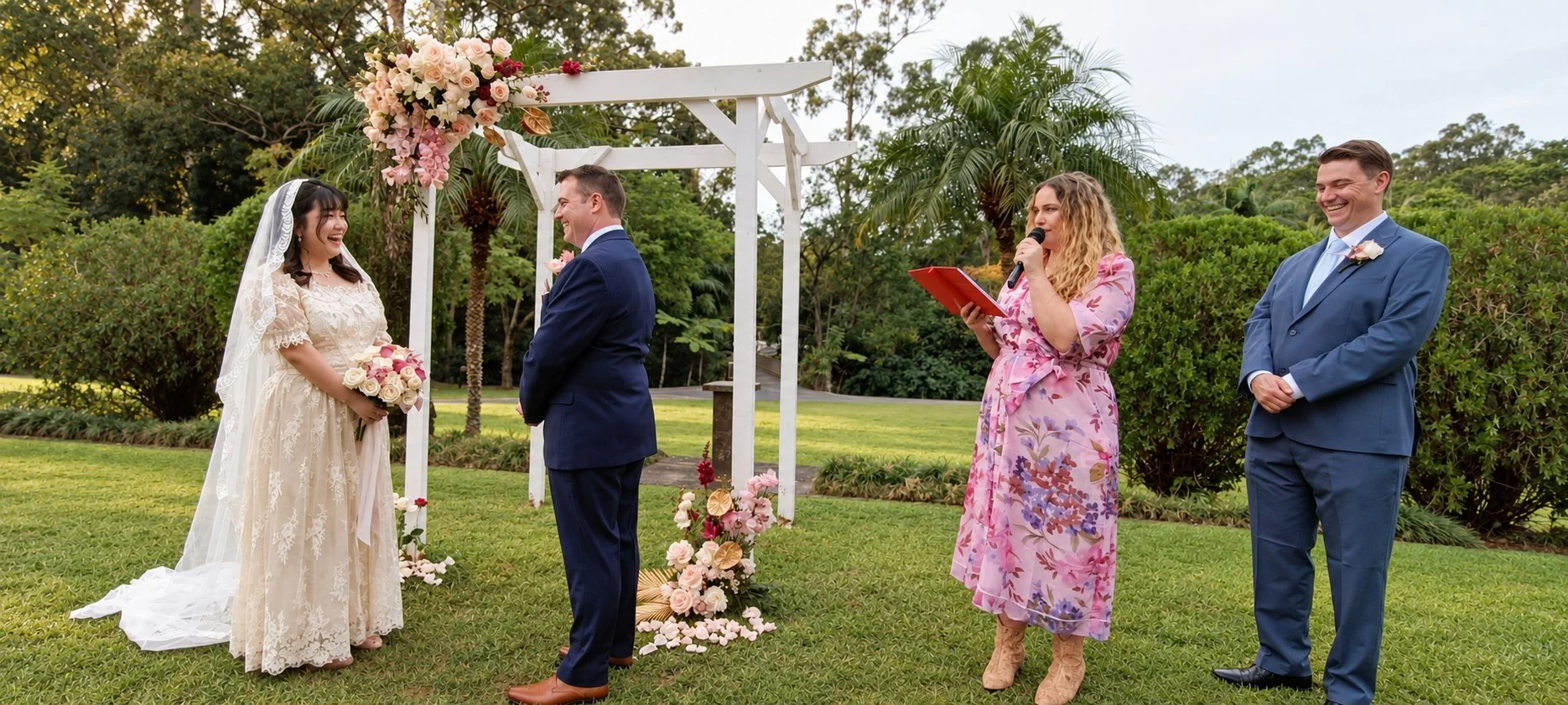 Maddie Hayes leading a garden wedding ceremony under a white arbour while the couple laugh