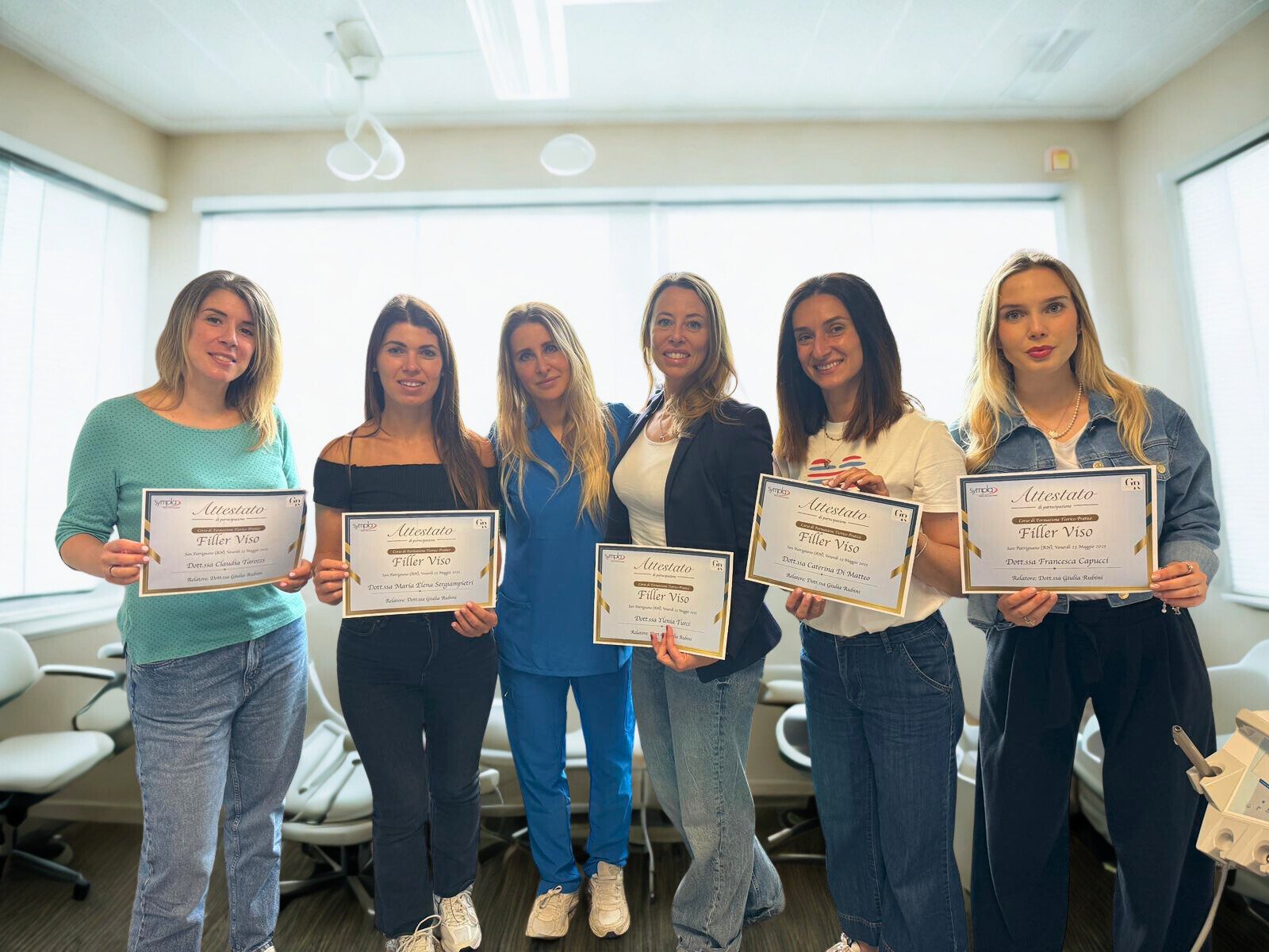 Sei donne in piedi che tengono certificati di formazione, in un ambiente luminoso e moderno