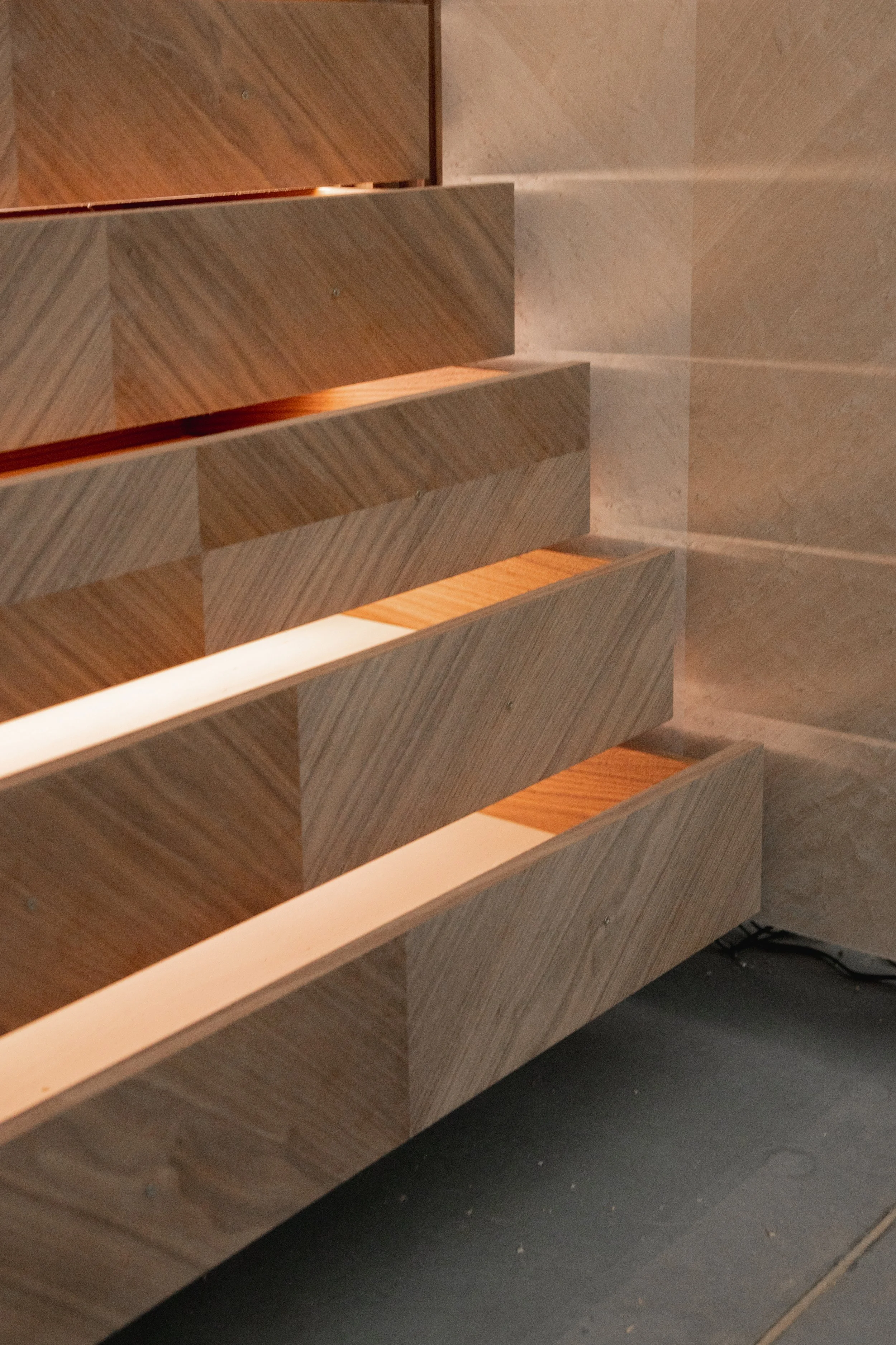 Close-up of wooden wall-mounted shelves in a room with tiled walls and a black floor.