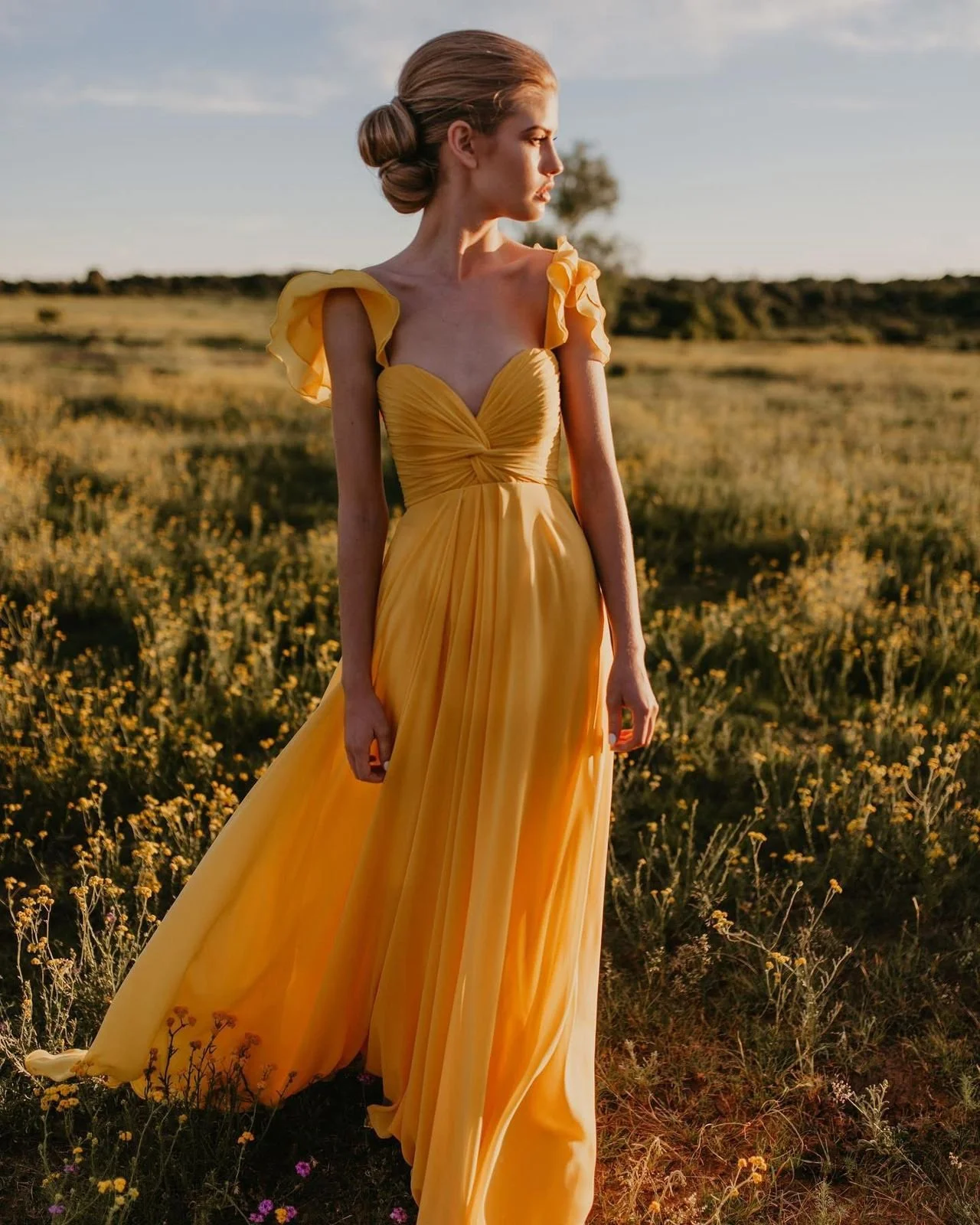 SB2 - Yellow Dress
Bold yet romantic, this flowing yellow gown captures the essence of golden hour. The softly draped bodice enhances the natural shape, while the flutter sleeves add a delicate, feminine touch. Crafted in a lightweight fabric that mo