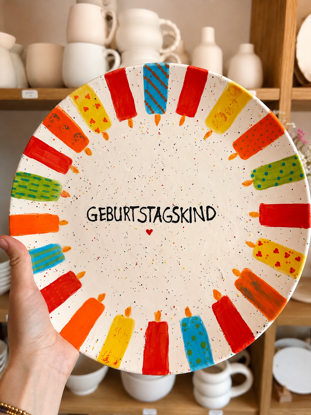 Bunter Teller mit Kerzenmuster und dem Wort 'Geburtstagskind' in der Mitte, umgeben von farbigen Kerzenzeichnungen.
