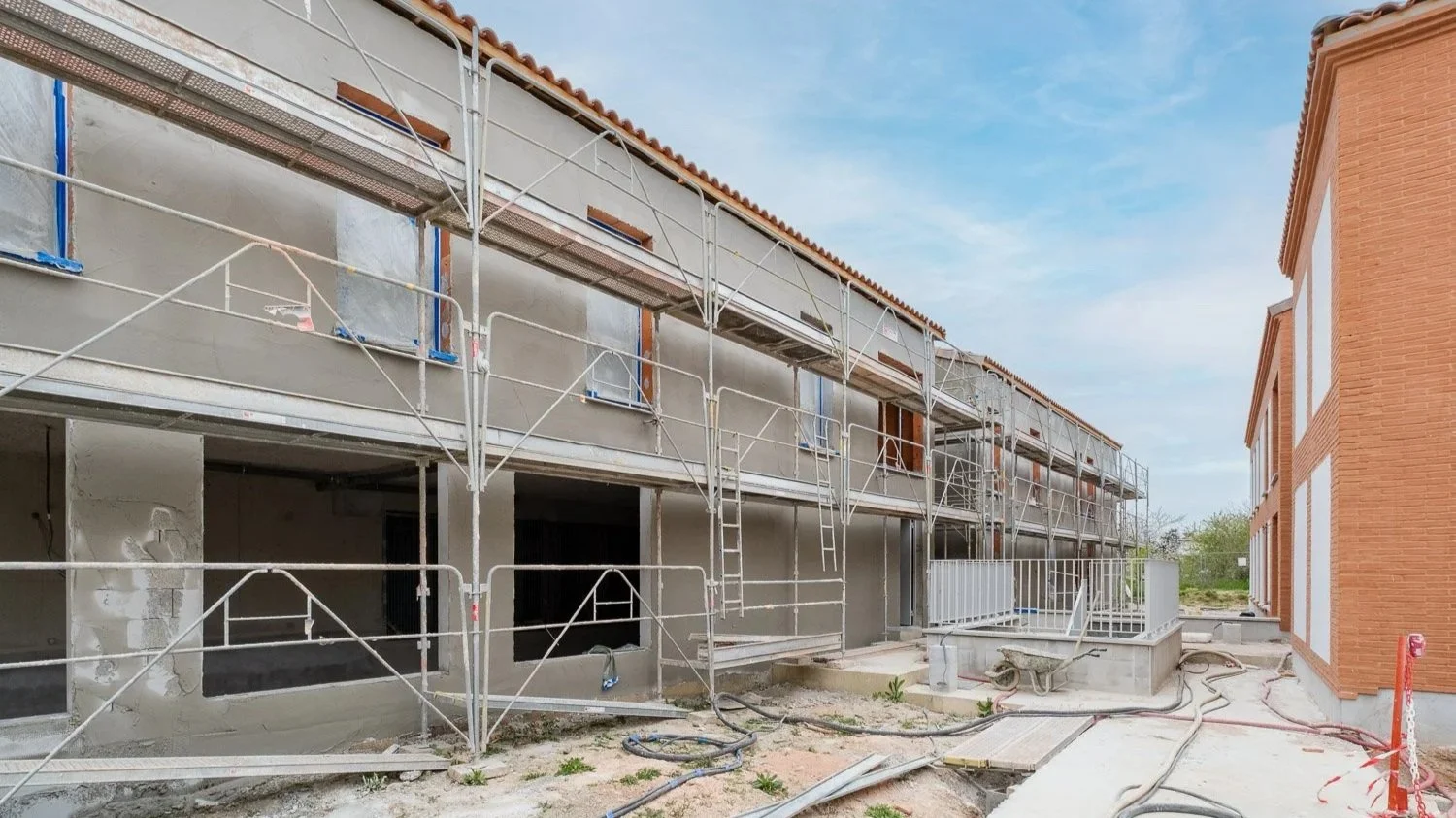 Construction d'un bâtiment résidentiel avec des échafaudages et des murs en béton en cours de finition.