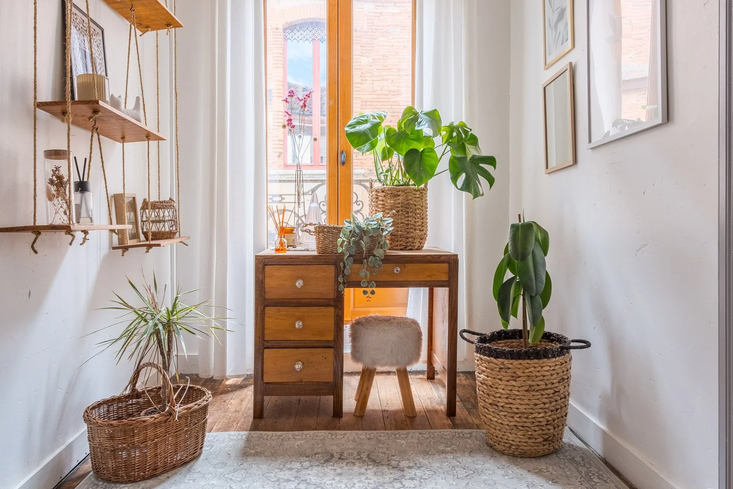 Intérieur d'une pièce lumineuse avec un bureau en bois, une chaise à fourrure, plusieurs plantes en pot, et des décorations murales