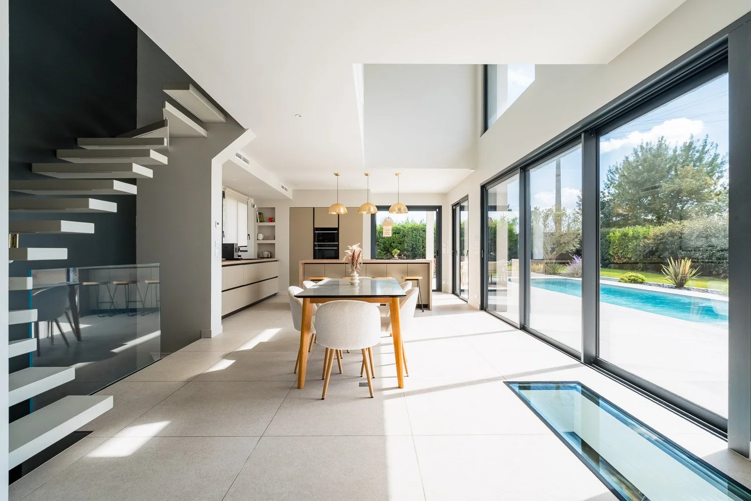 Villa d'architecte contemporaine à Toulouse, séjour ouvert avec escalier suspendu et baies vitrées donnant sur la piscine