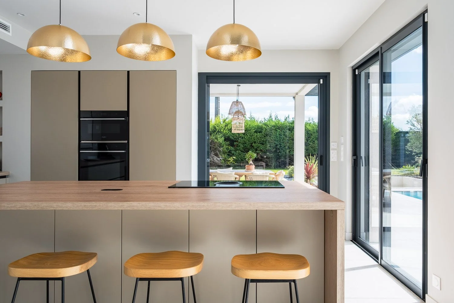Cuisine contemporaine haut de gamme avec îlot central et suspensions dorées dans une villa de prestige