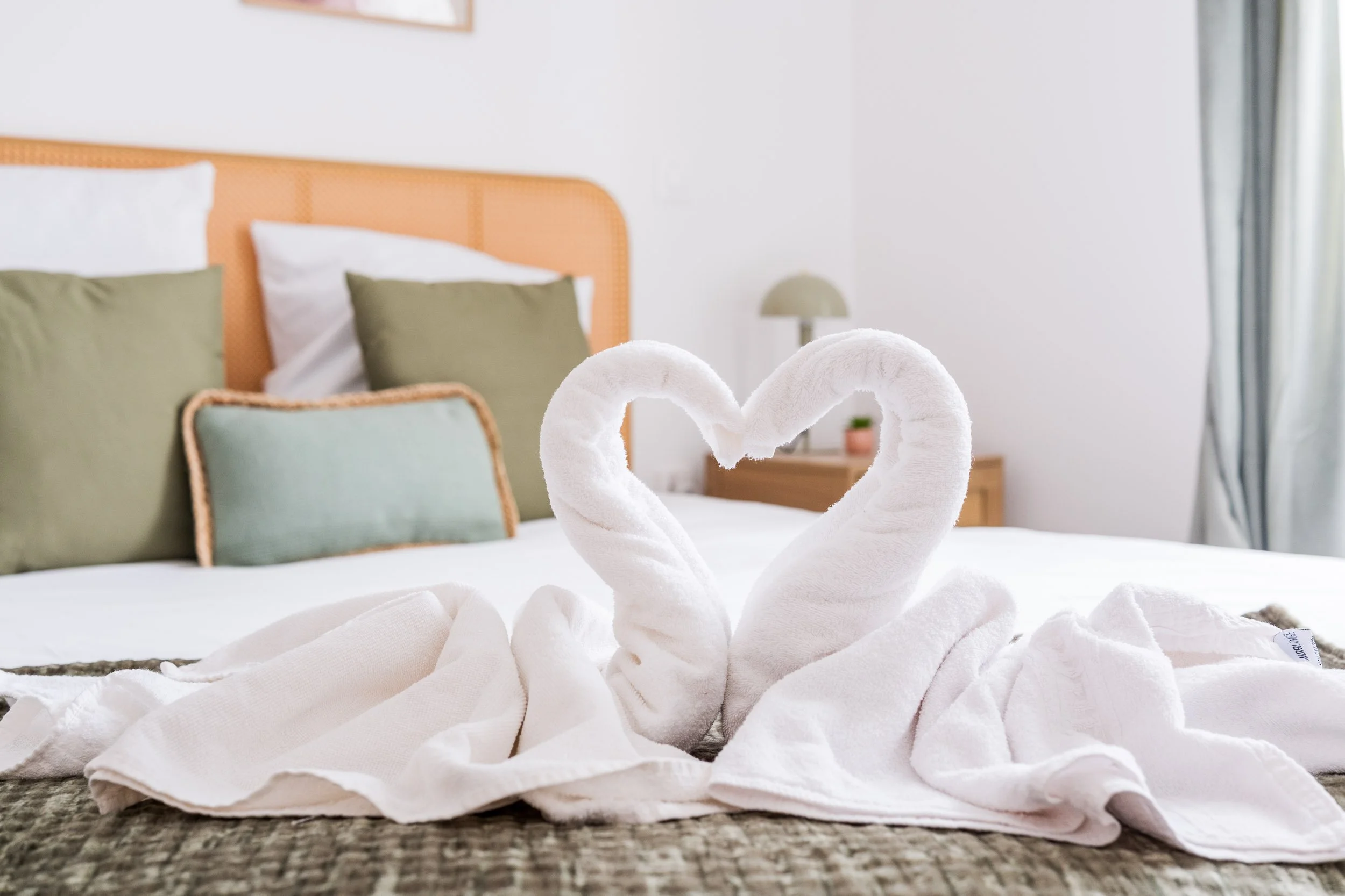 Serviettes en forme de cœur dans un décor de chambre à coucher avec des lits et des coussins.