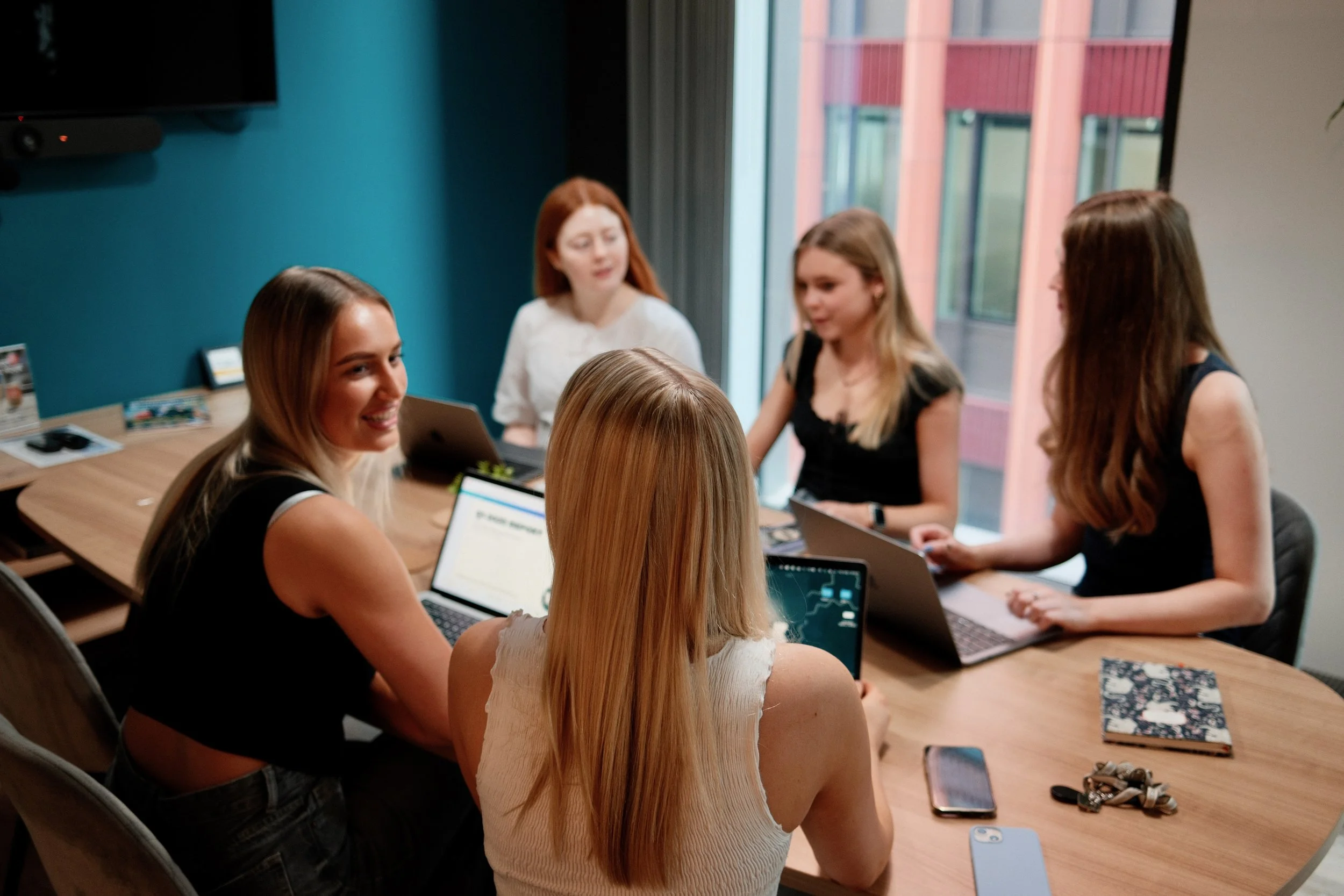 Close-up meeting shot with smiling team members – "The Mind Collective marketing experts collaborating on creative campaign planning and performance marketing strategies.