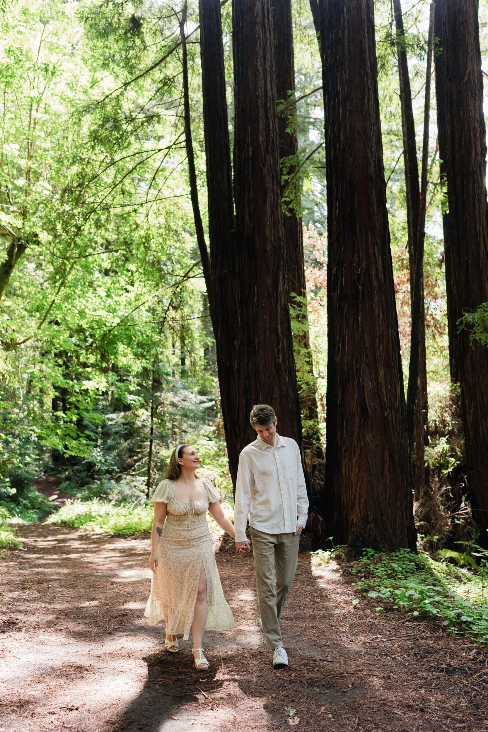 Santa Cruz engagement photographer- A couple is walking holding hands in Santa Cruz forest for their engagement photos.