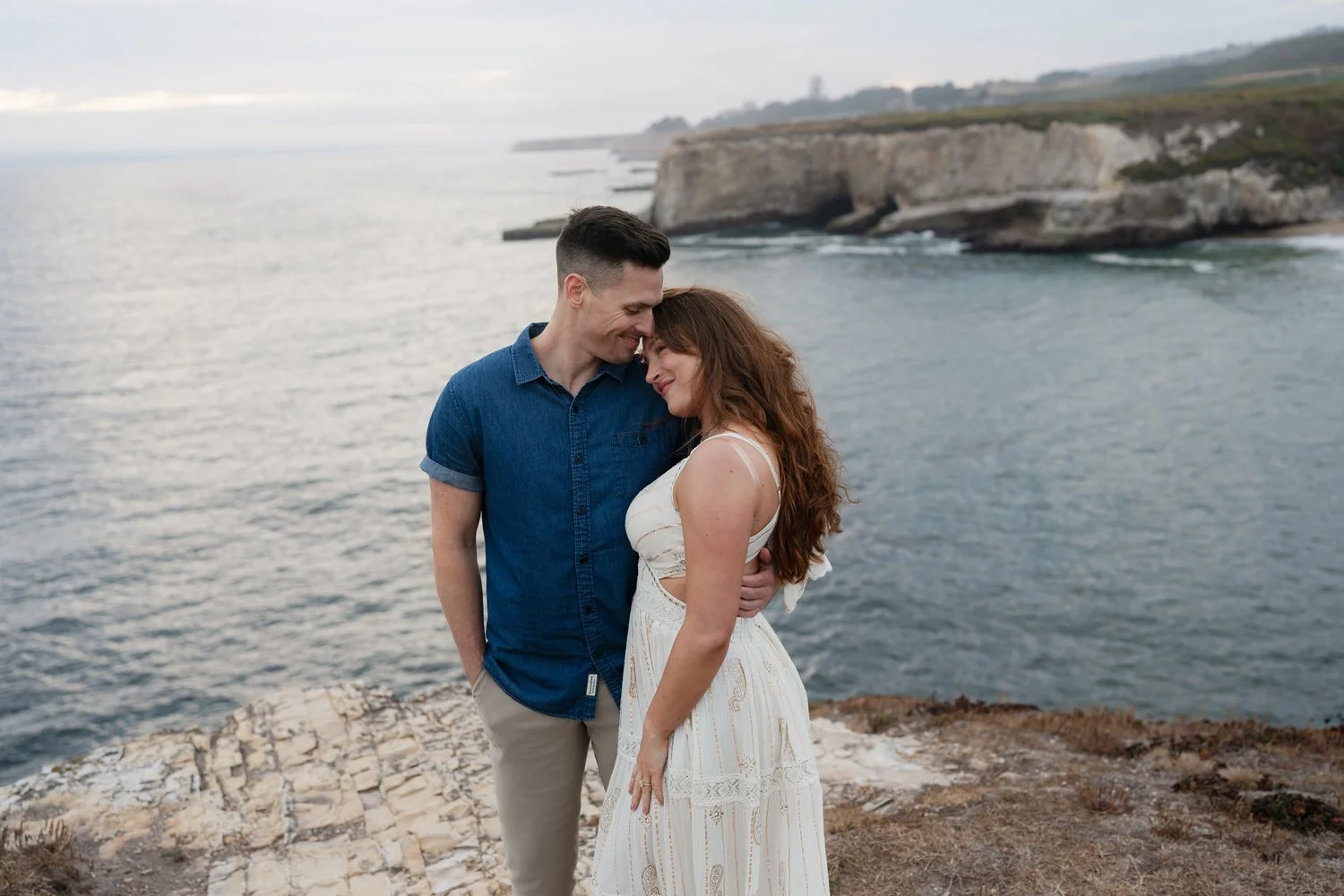 couple is standing by the cliff for ther engagement photography in Sant Cruz.