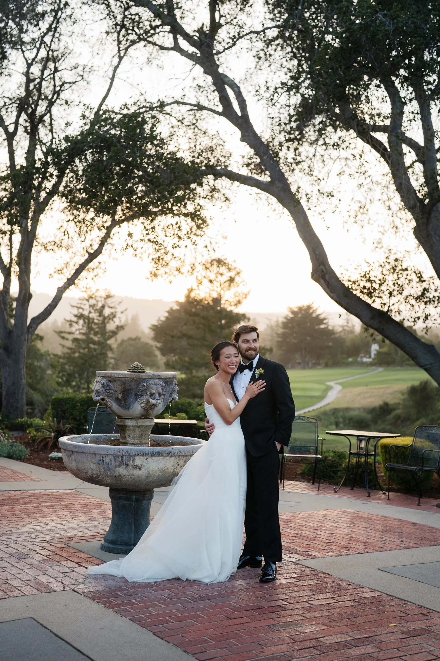 Couple is posing for the wedding photographer in the Hollins House in Santa Cruz. They stand near each other by the fountain.