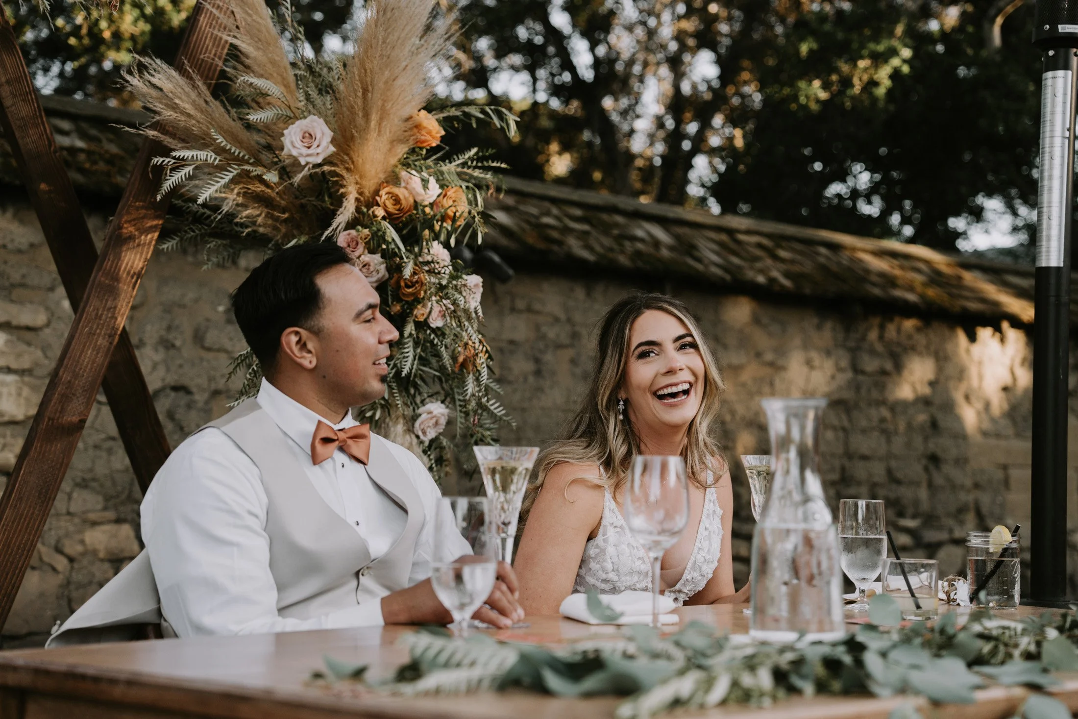 a beautiful wedding reception The Barns at Cooper Molera in Monterey and Carmel were the bride is laughing at the comments the best man is making during toasts.