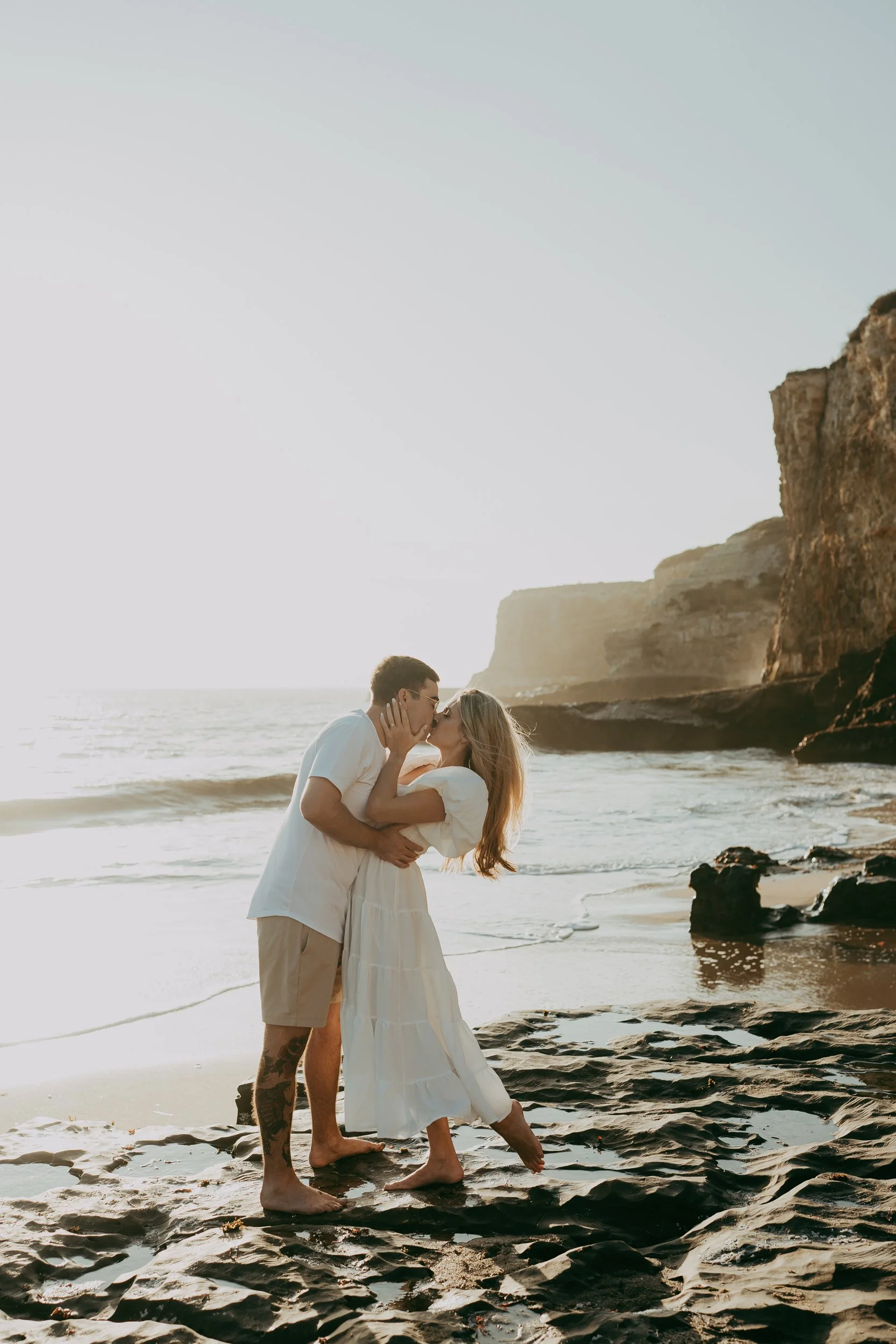 Santa Cruz engagement photographer- a couple is kissing in the rocks in Santa Cruz for their engagement photography.