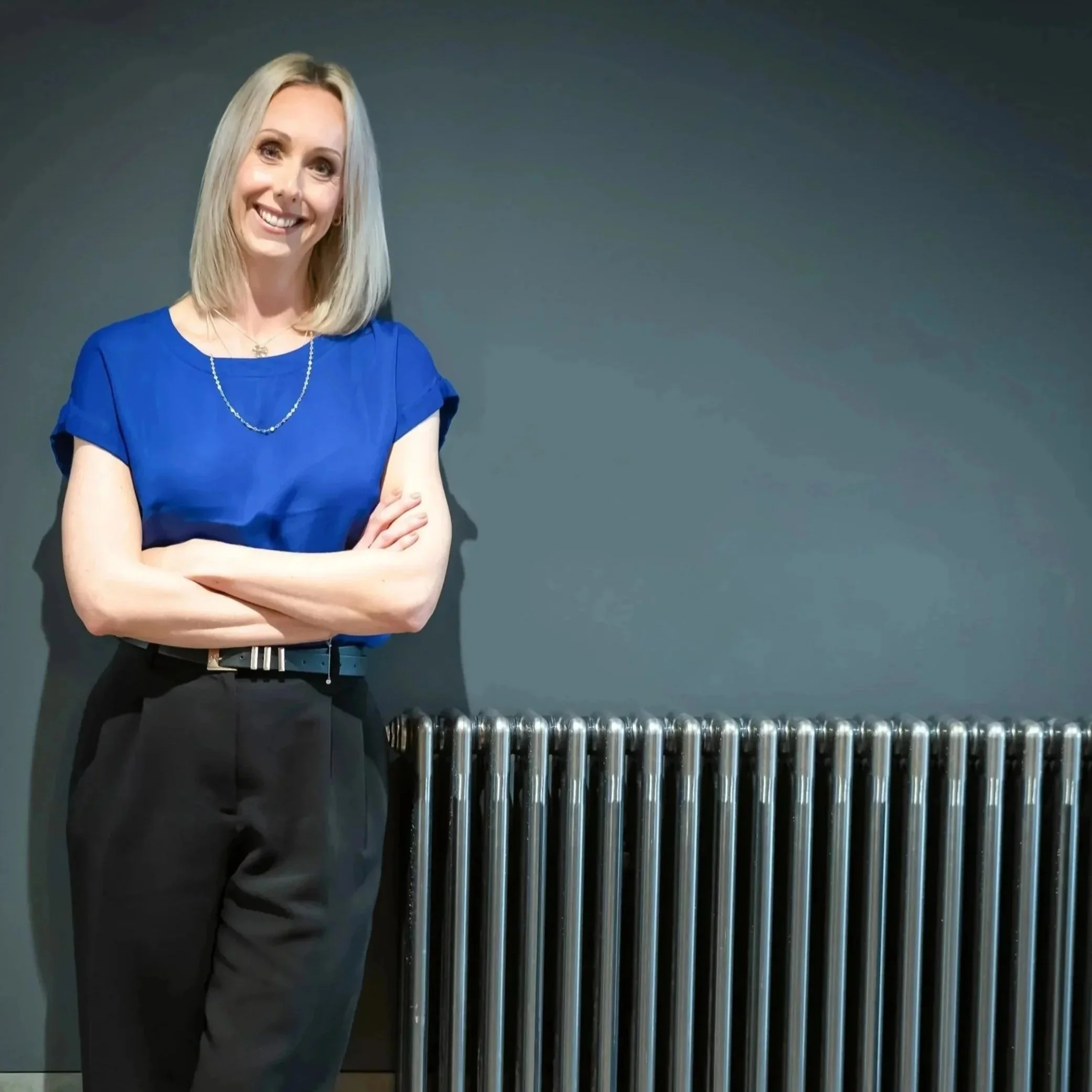 Lady with blonde hair leaning against a radiator
