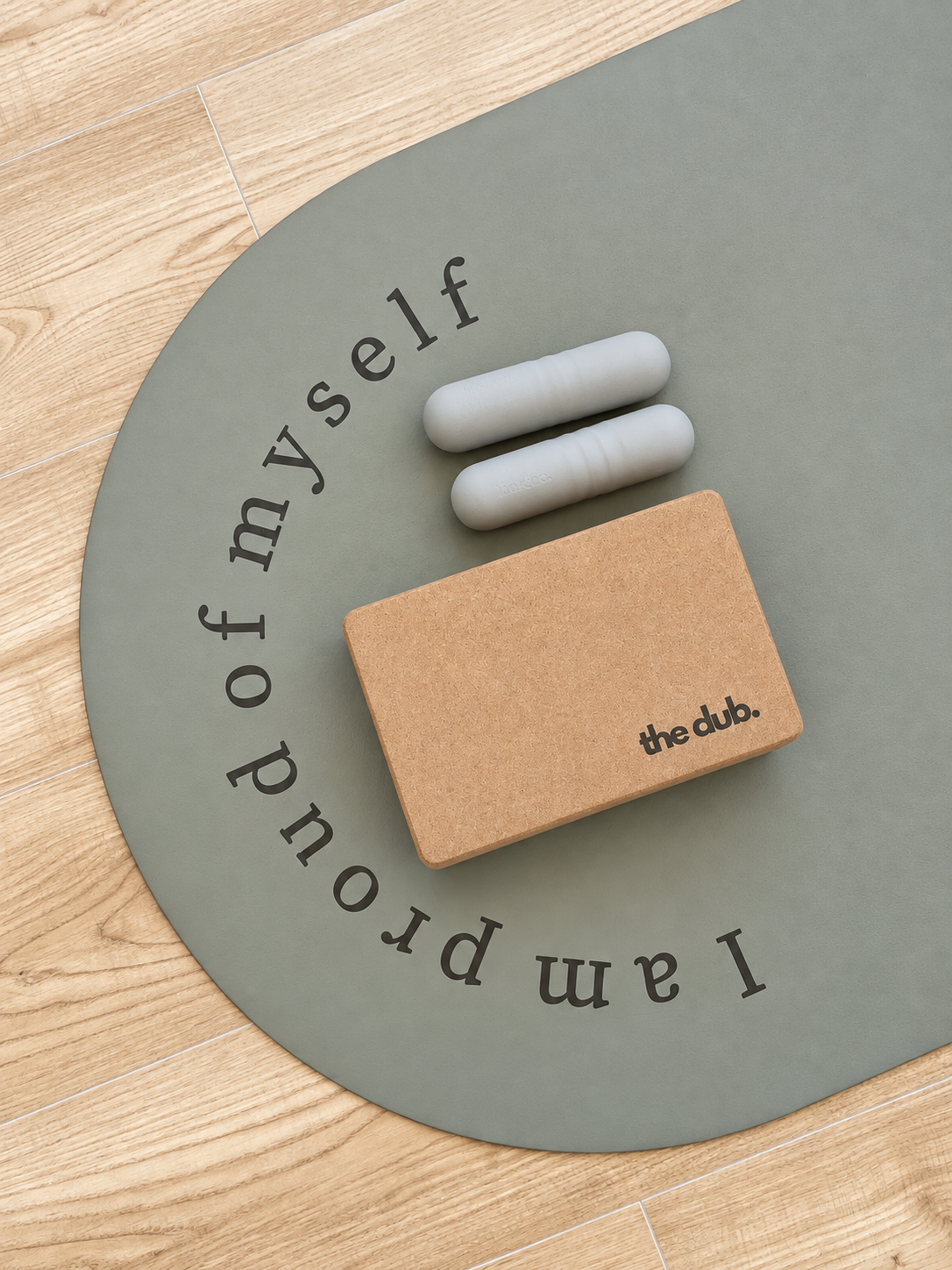 Un tapis  avec l'inscription "I am proud of myself" et une pouf ronde blanche, le tout posé sur un sol en carrelage gris clair.