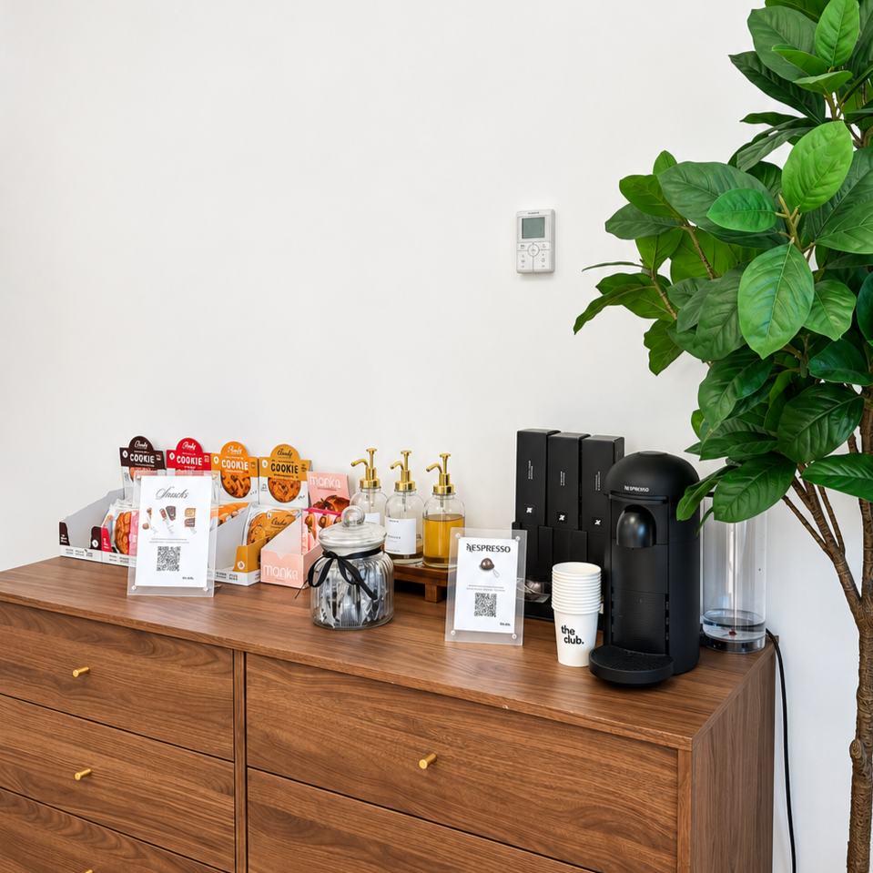 Bar avec boissons et snacks, meubles en bois, papier jetable, distributeurs de savon, et une machine réfrigérée à gauche.