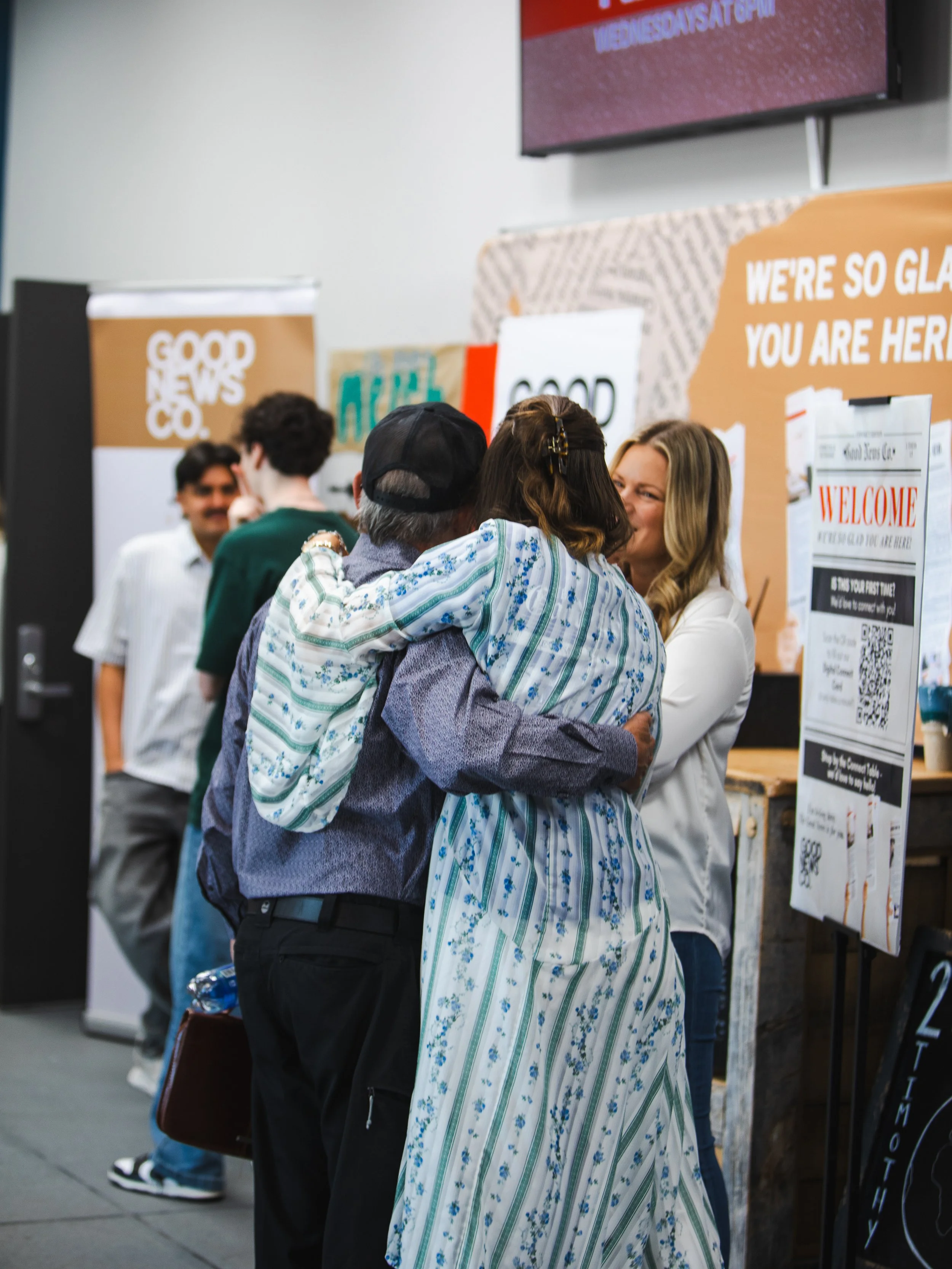 People greeting one another beside the Good News Co. welcome area.