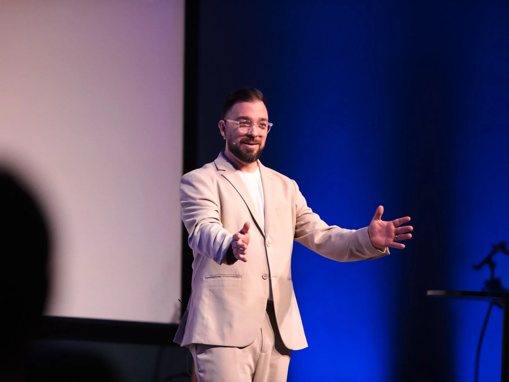 A GNCO speaker teaches with both hands extended.