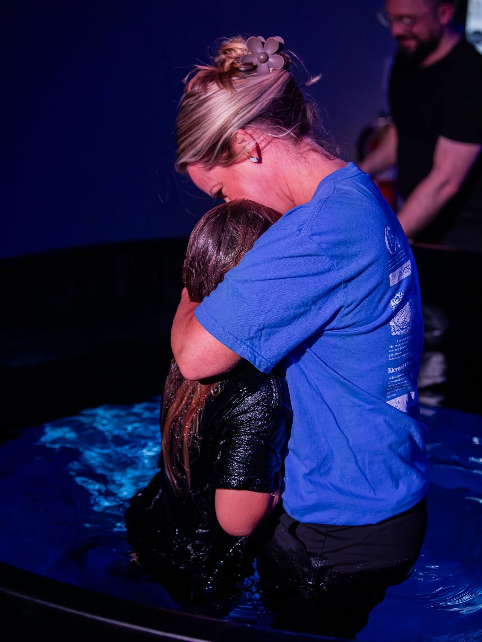 Two people embrace in the water after a baptism.