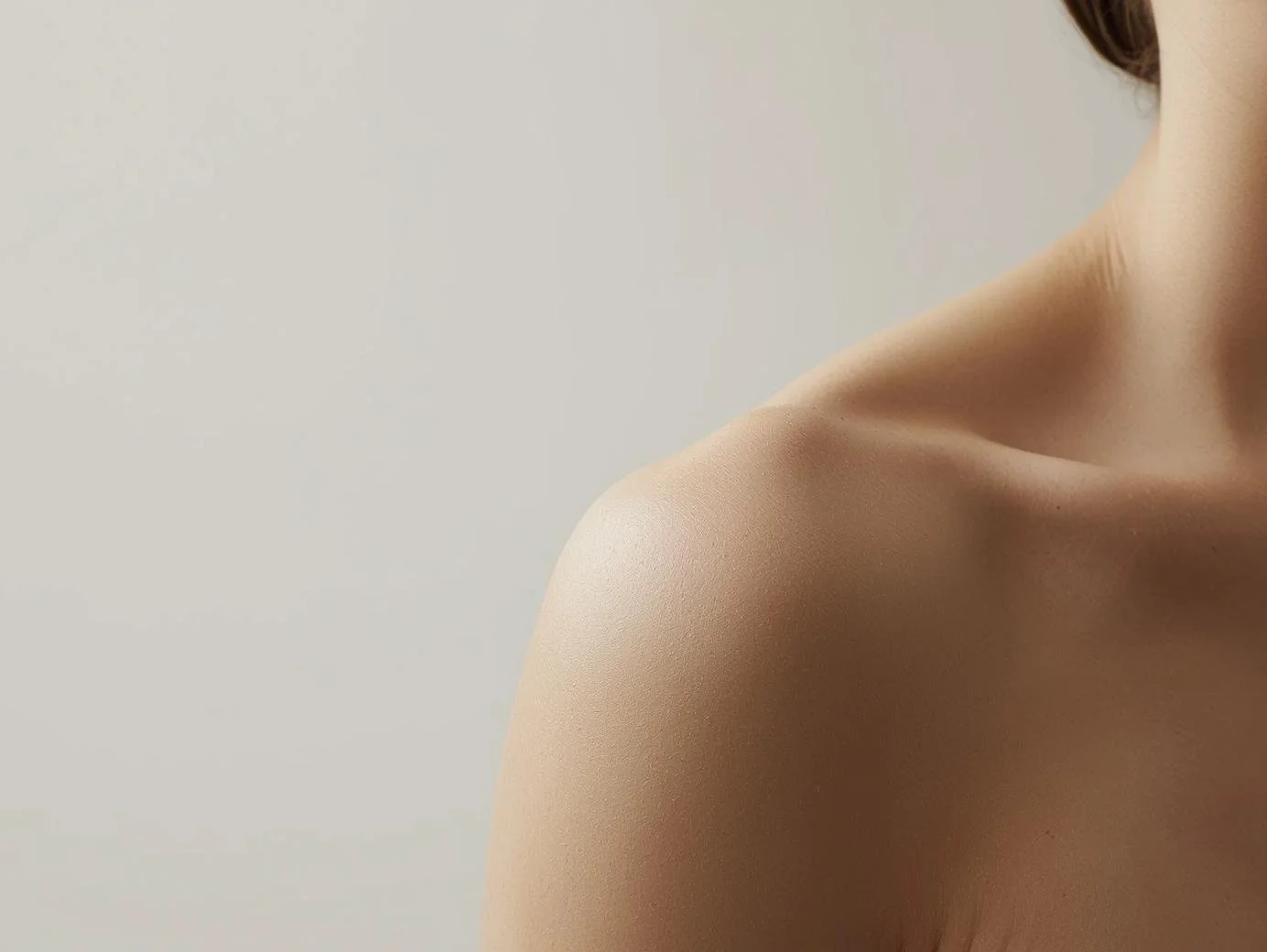 Close-up of a person's shoulder and neck against a neutral background.