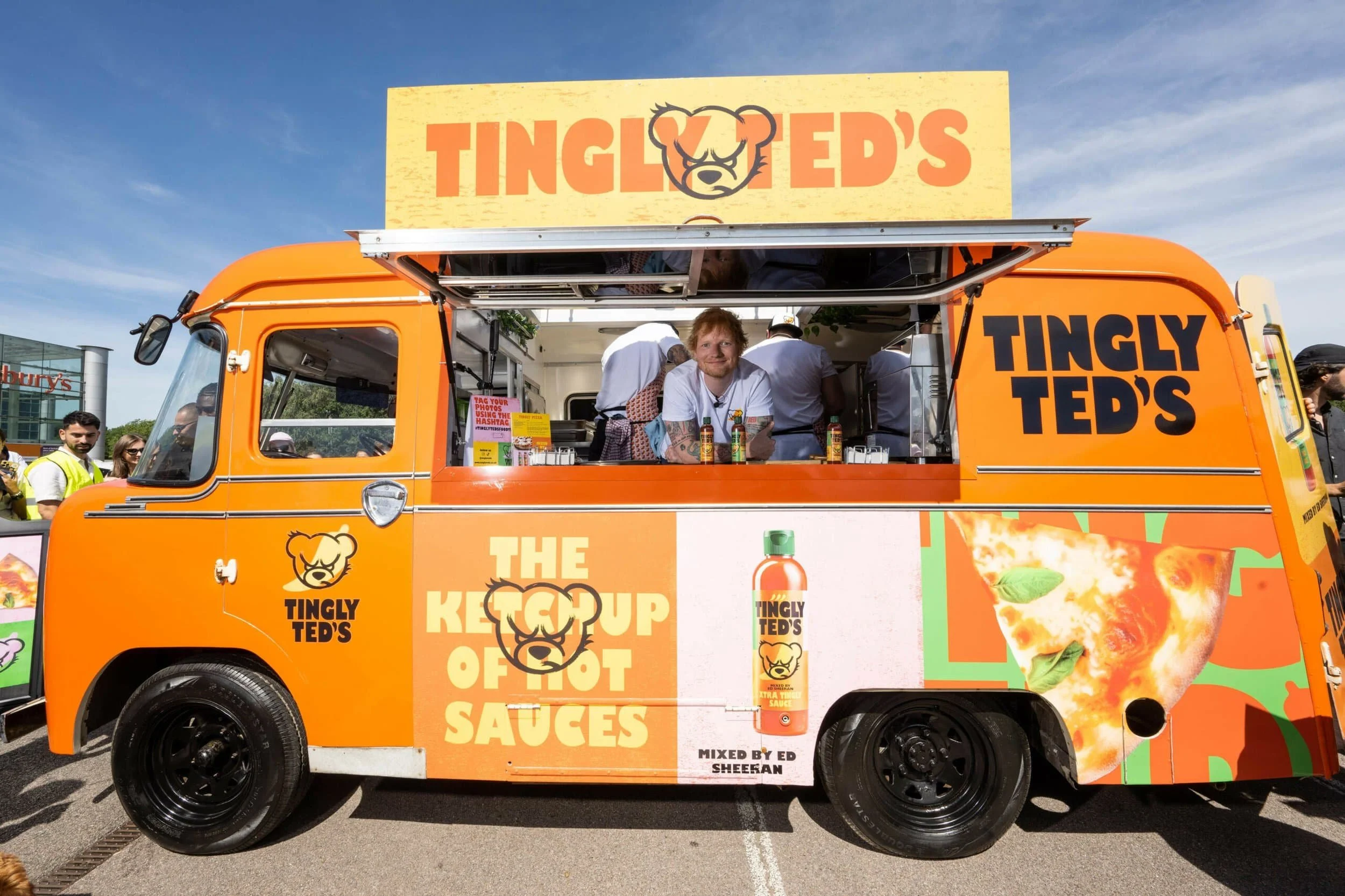 Tingly Ted's food truck with Ed Sheeran at the counter and a crowd in the background.